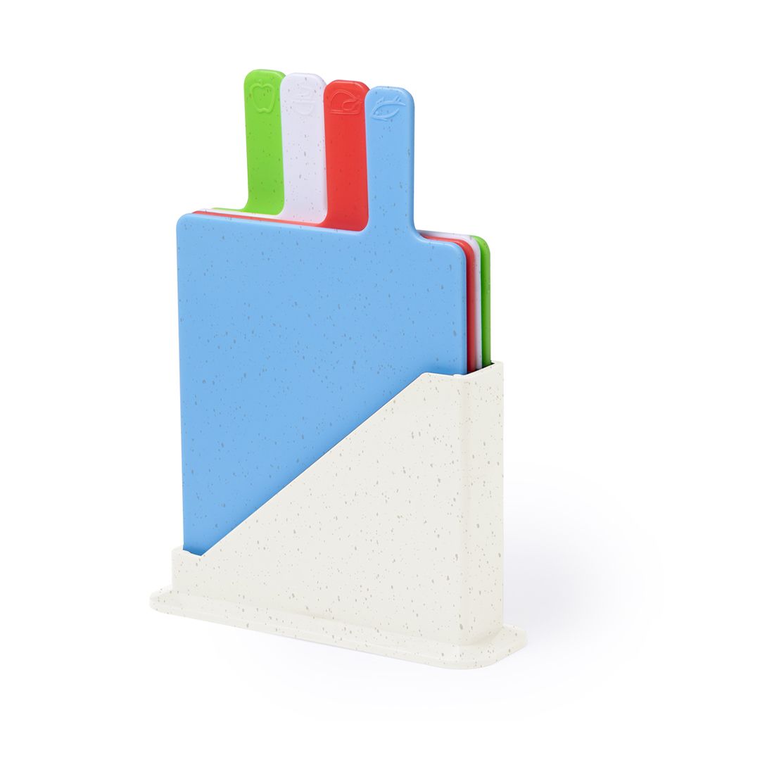 Un juego de cuatro tablas de cortar de colores: azul, rojo, blanco y verde, guardadas en posición vertical en un soporte moteado de color crema.