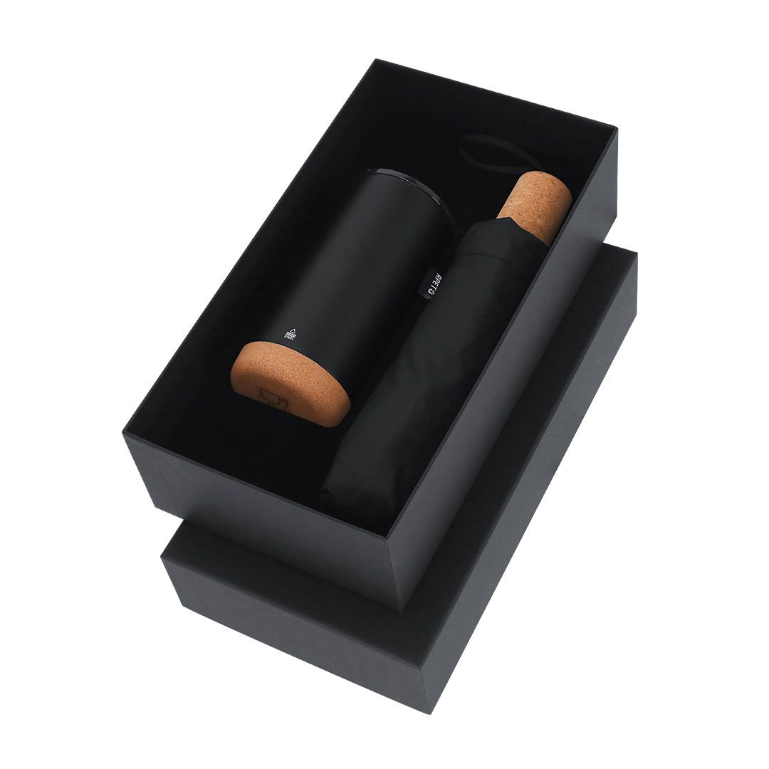 Una caja de regalo negra que contiene un paraguas compacto negro con mango de corcho y un estuche cilíndrico negro a juego.