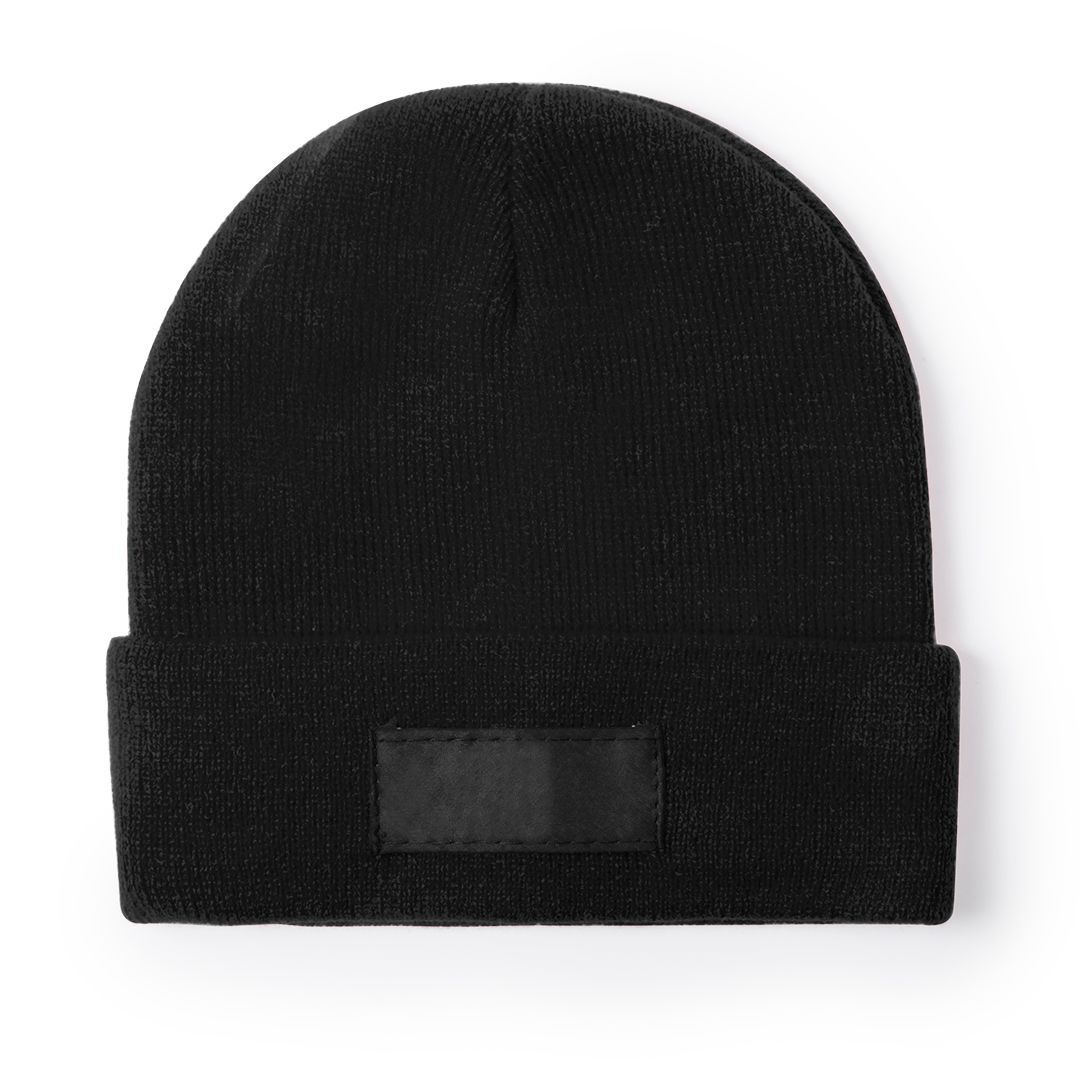 Un gorro de punto negro con un parche rectangular negro liso a juego en el borde doblado sobre un fondo blanco.