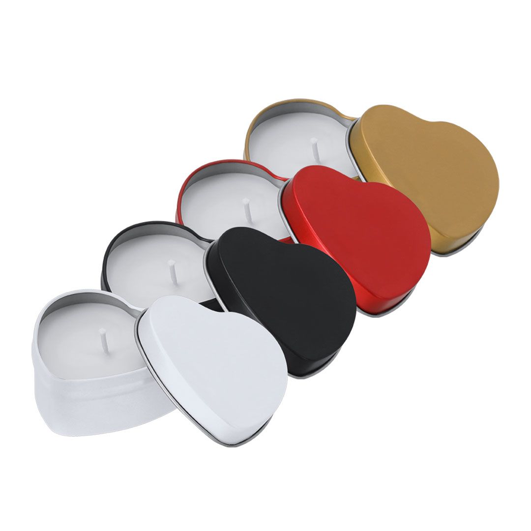 Cuatro latas de velas con forma de corazón y tapa, de colores blanco, negro, rojo y dorado, dispuestas en línea diagonal.