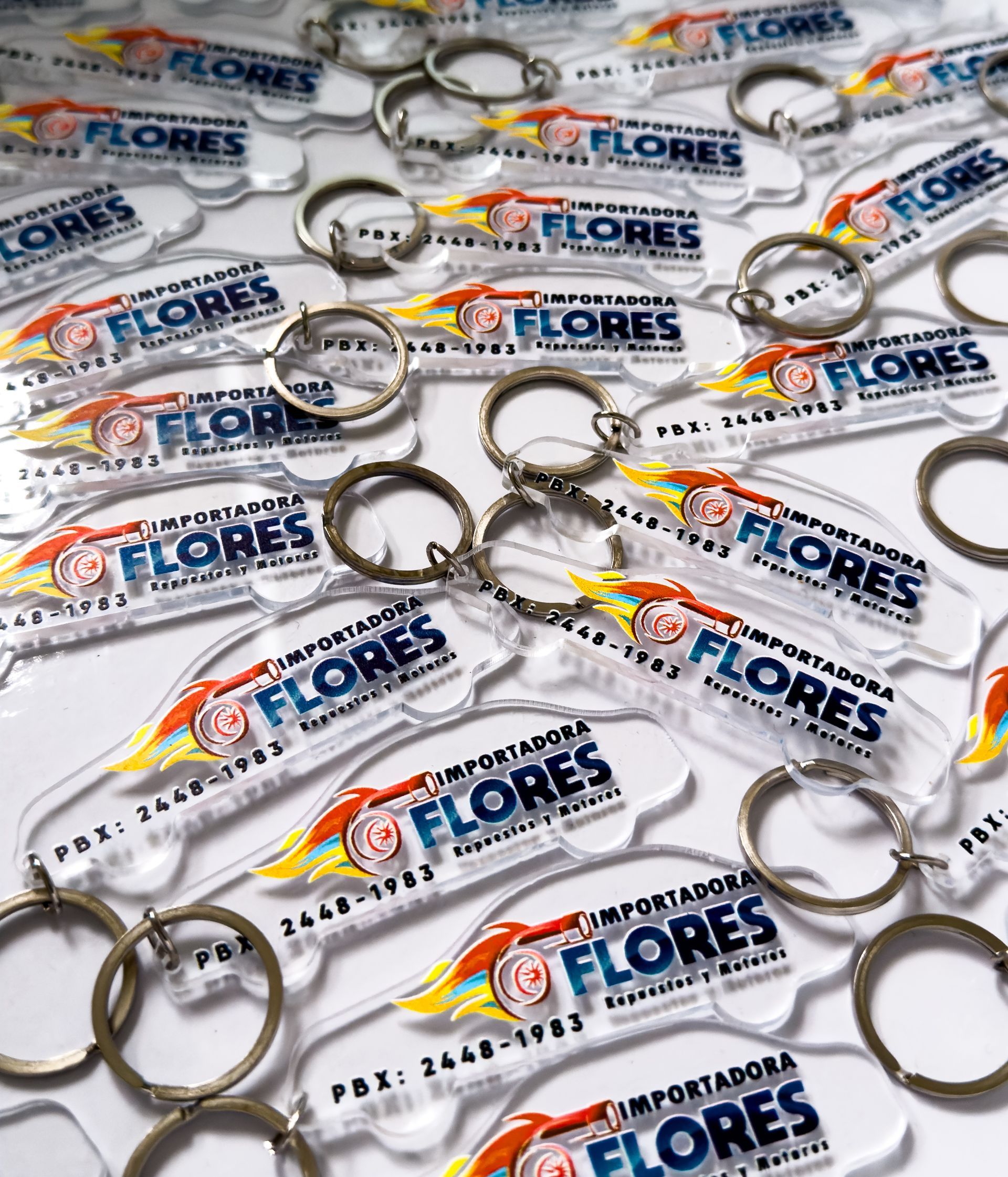 Un montón de llaveros acrílicos con forma de coche, cada uno con el logotipo y el número de teléfono de 