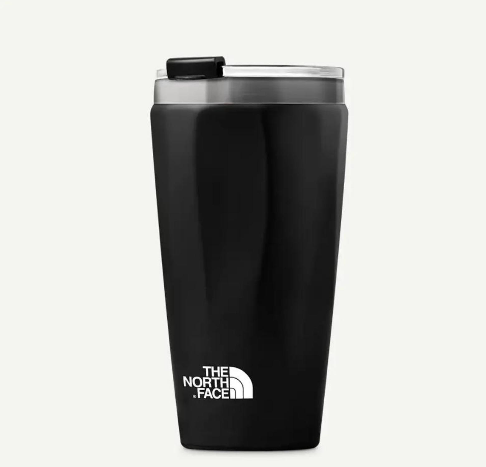 Un vaso térmico de viaje The North Face de color negro mate con borde metálico plateado y tapa deslizante negra, sobre un fondo liso.