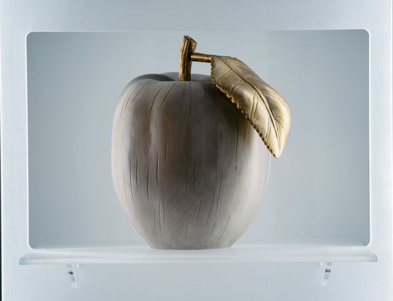 Una mela di legno con una foglia d'oro sopra