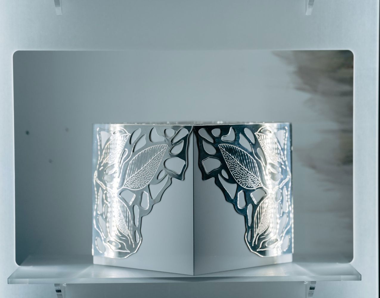 Un paio di braccialetti d'argento sono appoggiati su uno scaffale bianco.