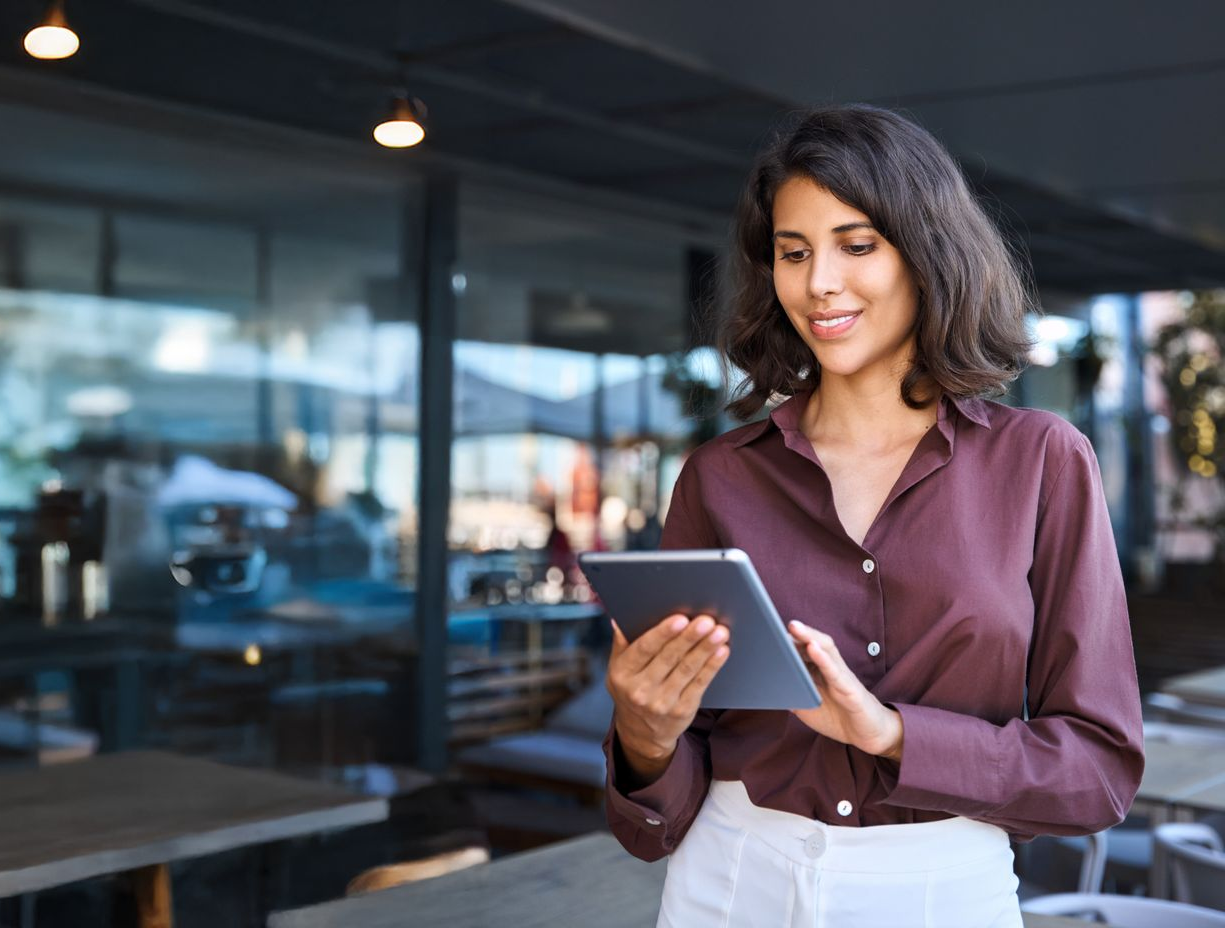 Woman with a big smile, wearing an apron, working at a POS system in a restaurant.