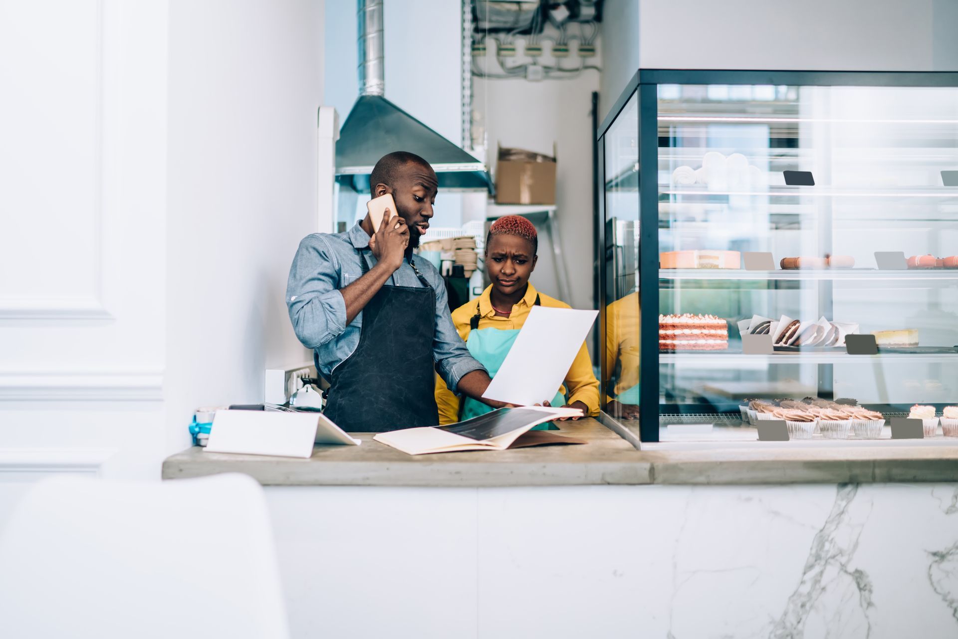 Woman with a big smile, wearing an apron, working at a POS system in a restaurant.