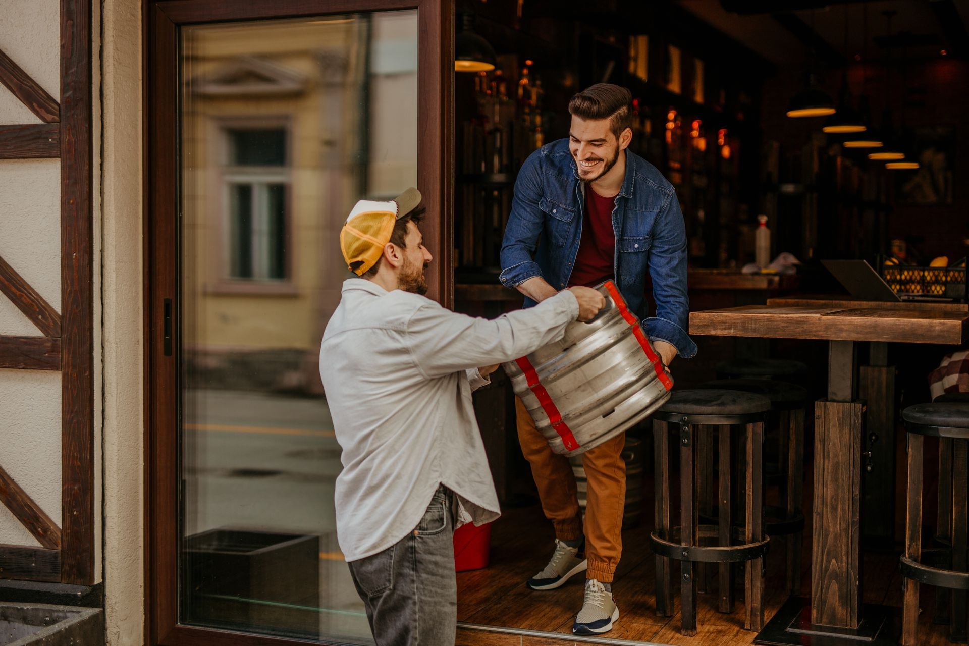 Person wearing glasses, apron, talking on phone, holding pen and paper behind a counter.