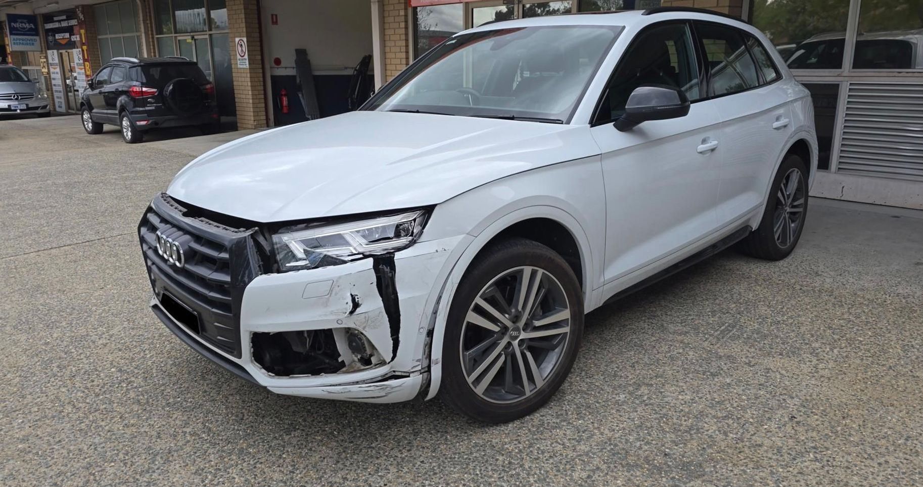 A white Audi Q5 is parked in front of a car dealership— Southside Bodyworks in Greenway, ACT