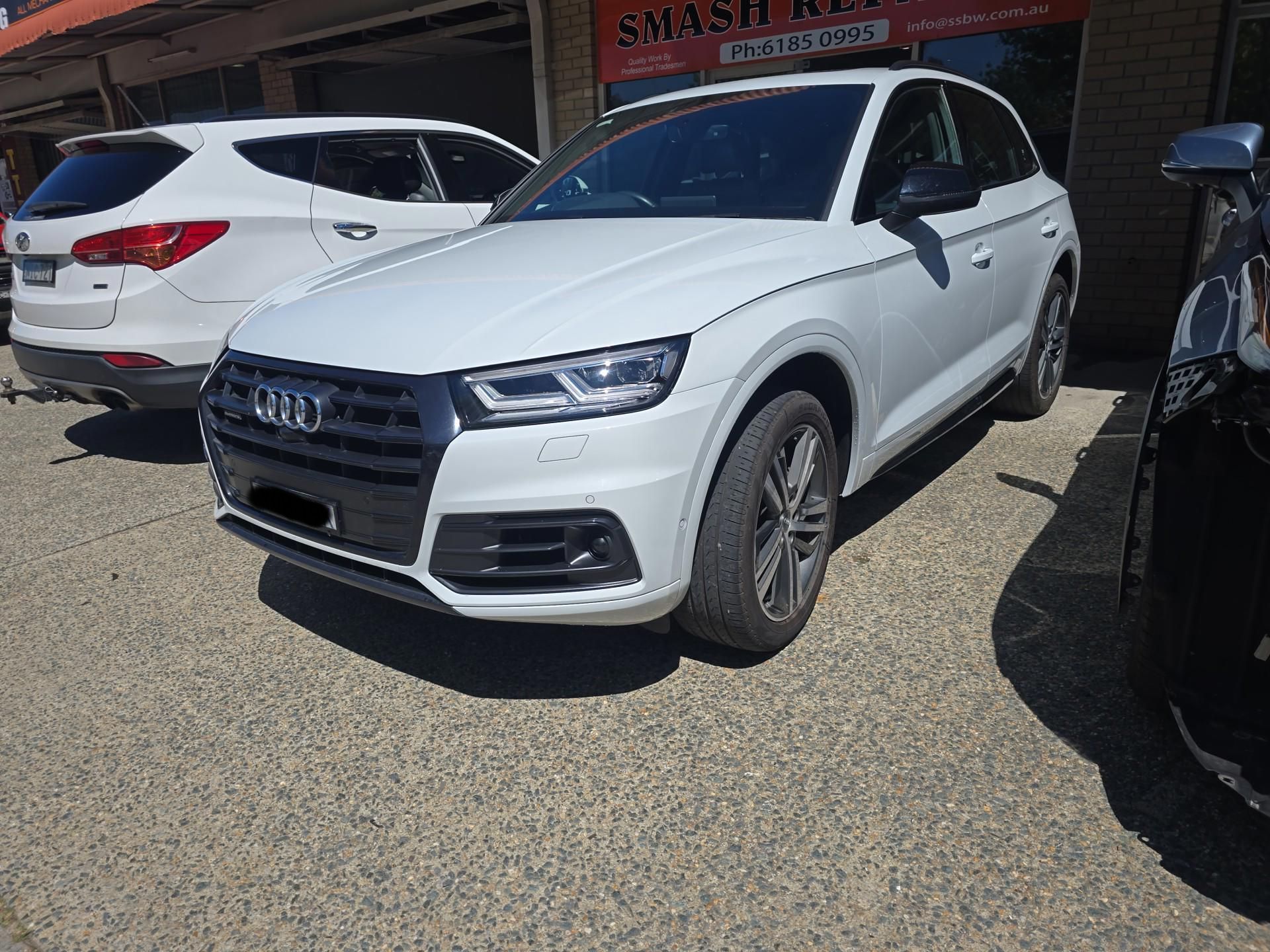 A white Audi Q5 is parked in front of a car dealership — Southside Bodyworks in Greenway, ACT