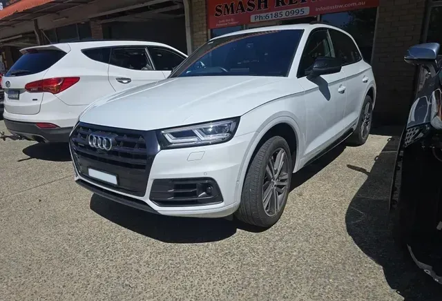 A white Audi Q5 is parked in front of a car dealership — Southside Bodyworks in Greenway, ACT
