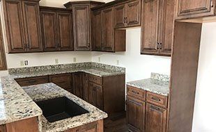 A kitchen with granite counter tops and wooden cabinets.
