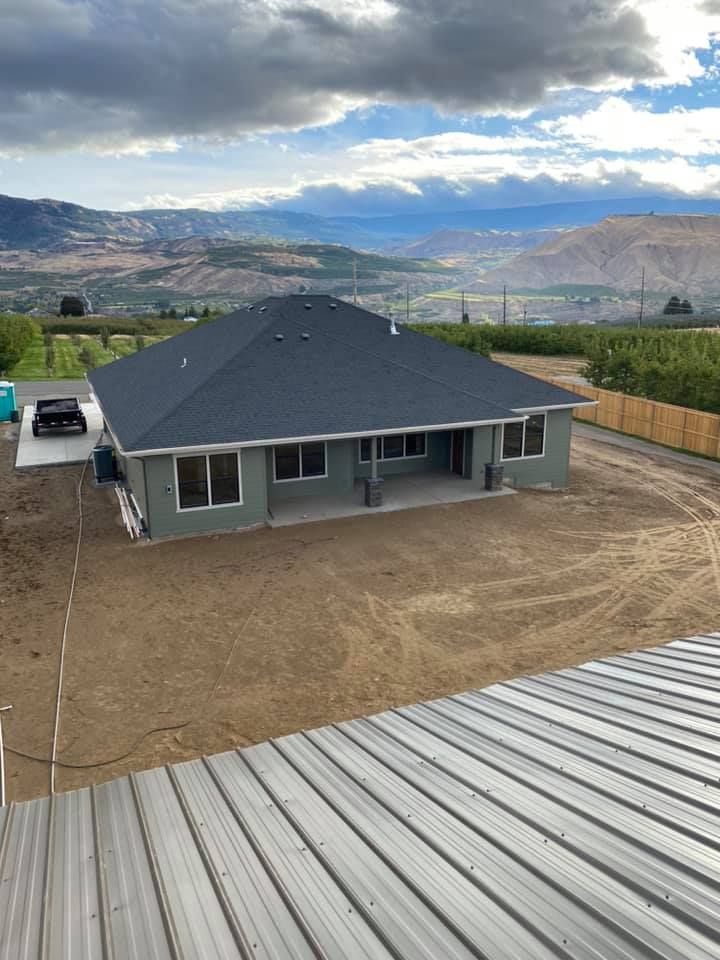 A house with a metal roof is sitting on top of a dirt field.