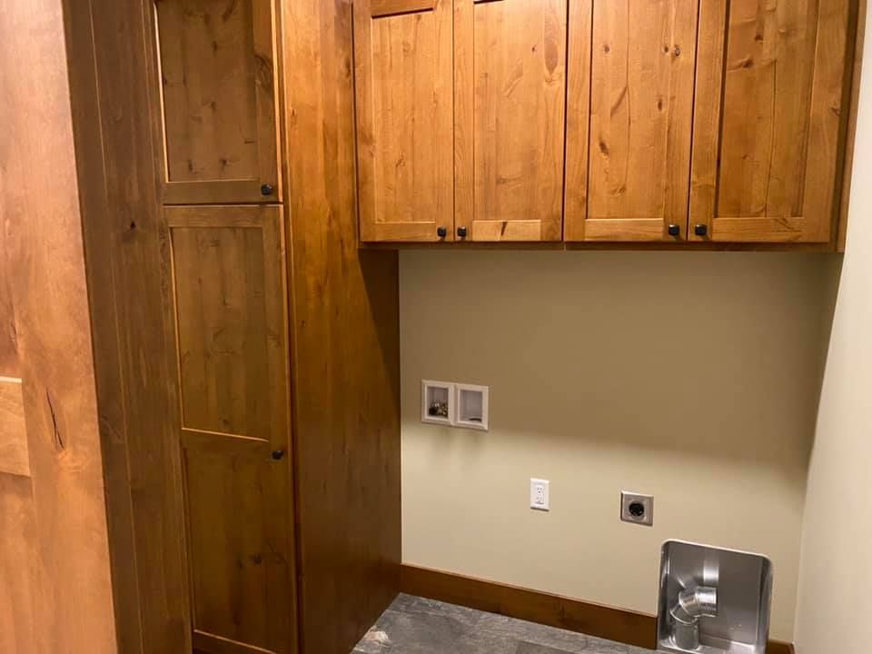A laundry room with wooden cabinets and a sink.