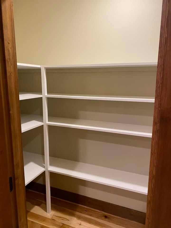 A closet with lots of shelves and a wooden floor.