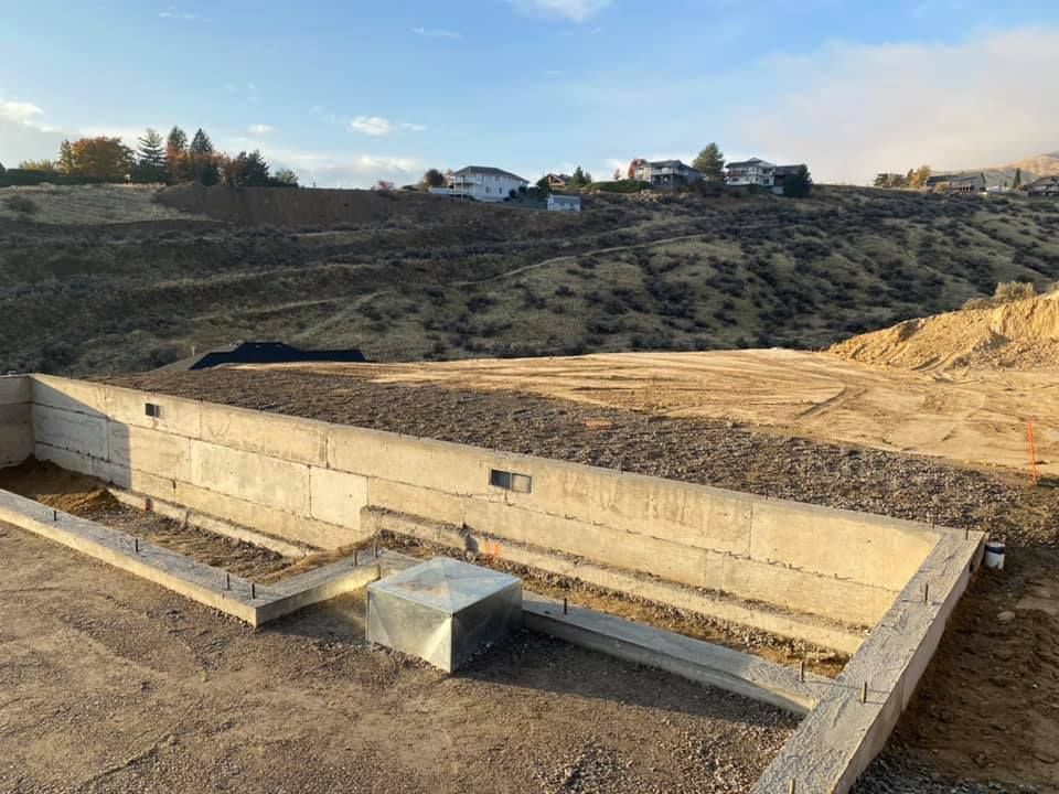 A concrete wall is being built on top of a dirt hill.