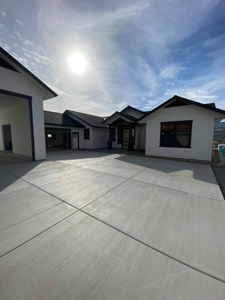 A large white house with a concrete driveway in front of it.