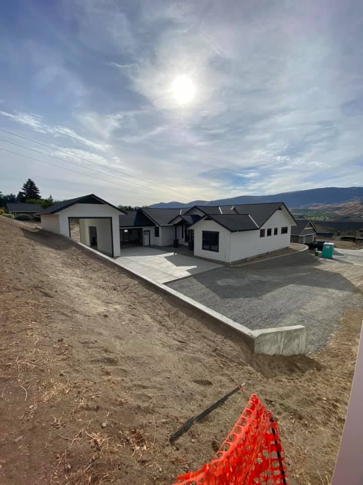 A large white house is sitting on top of a dirt hill.