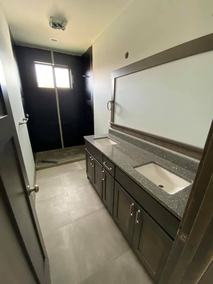A bathroom with a sink , cabinets , and a walk in shower.