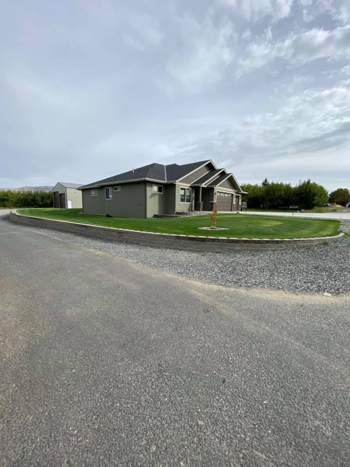 A house is sitting on the side of a road next to a gravel driveway.