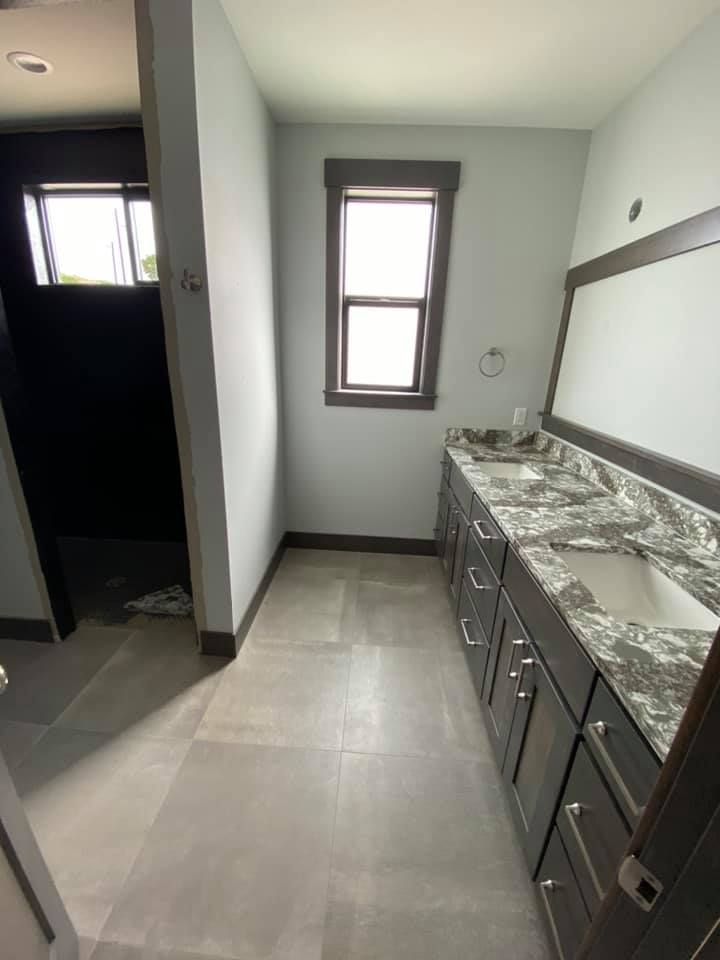 A bathroom with two sinks , a mirror and a window.