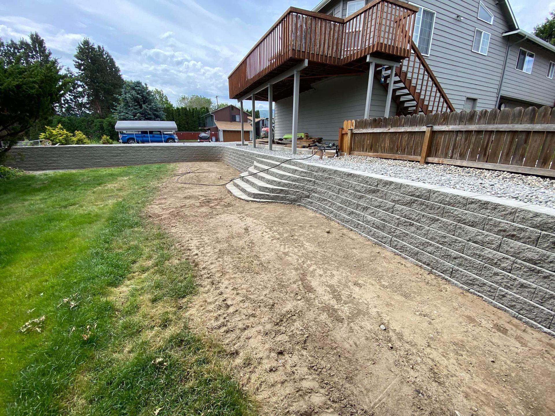 A house with a deck and a retaining wall in front of it.