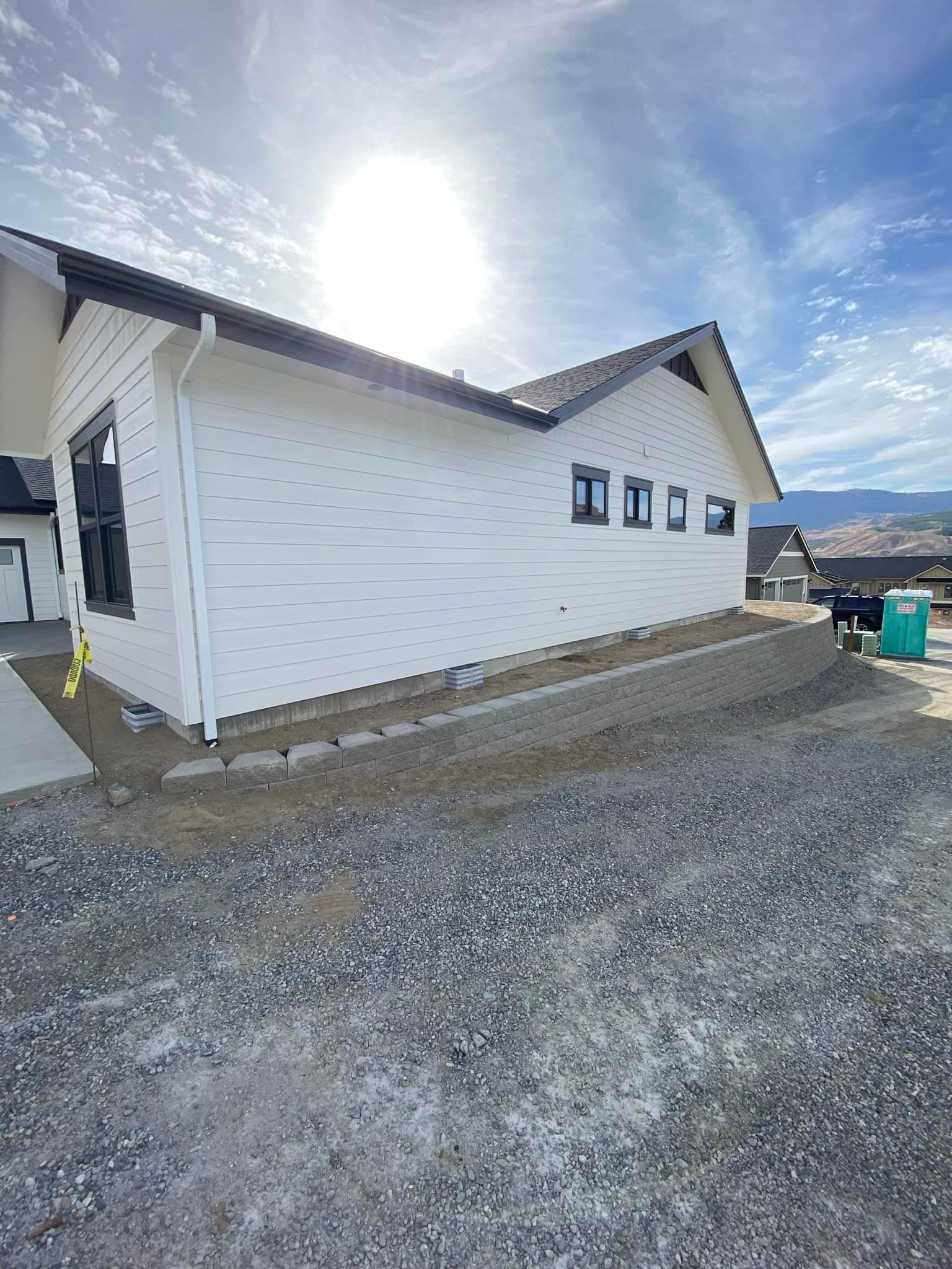 A white house is being built on a gravel lot.