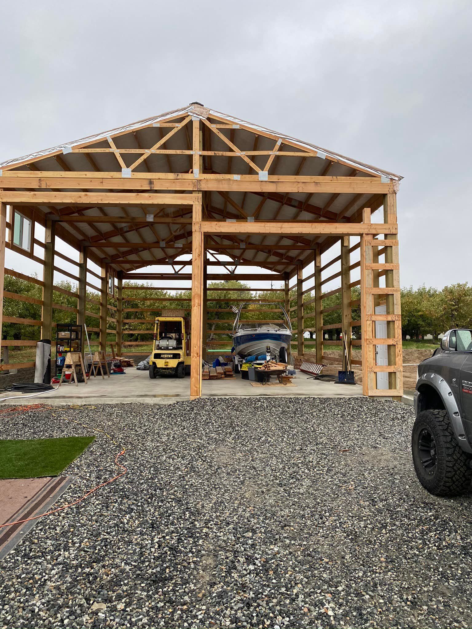 A car is parked in front of a wooden building under construction.