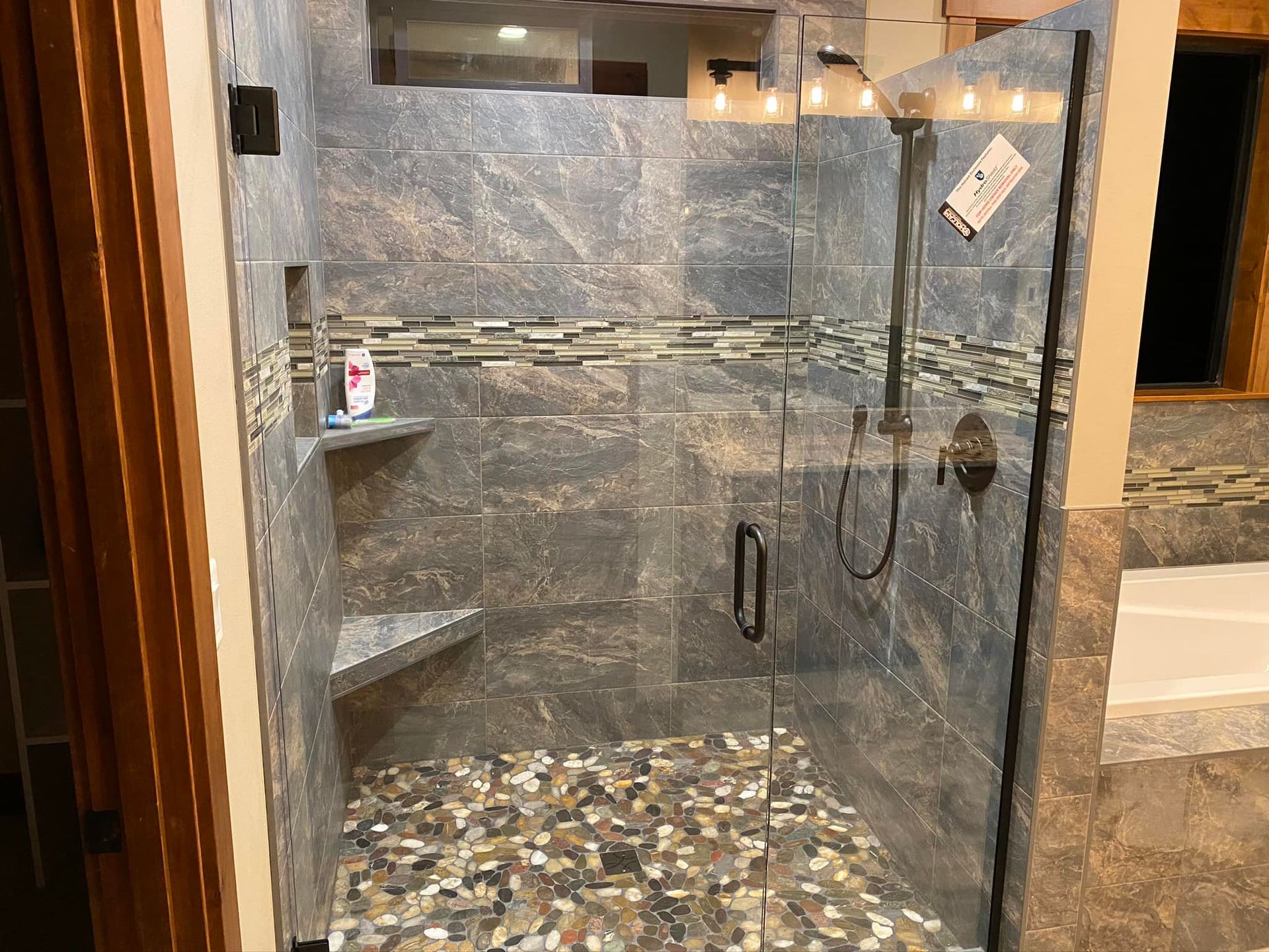 A bathroom with a walk in shower with a glass door.