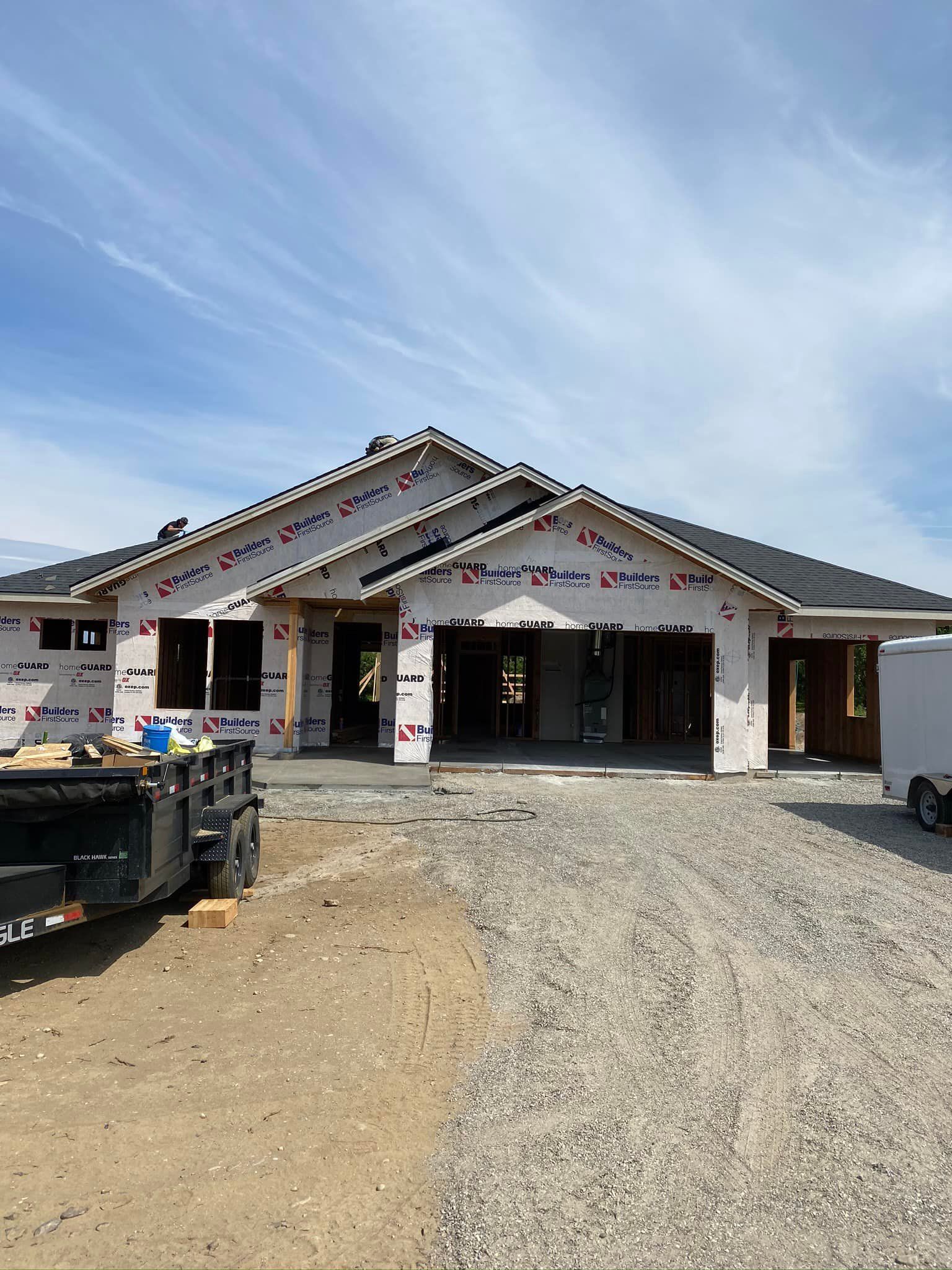 A house is being built with a trailer parked in front of it.