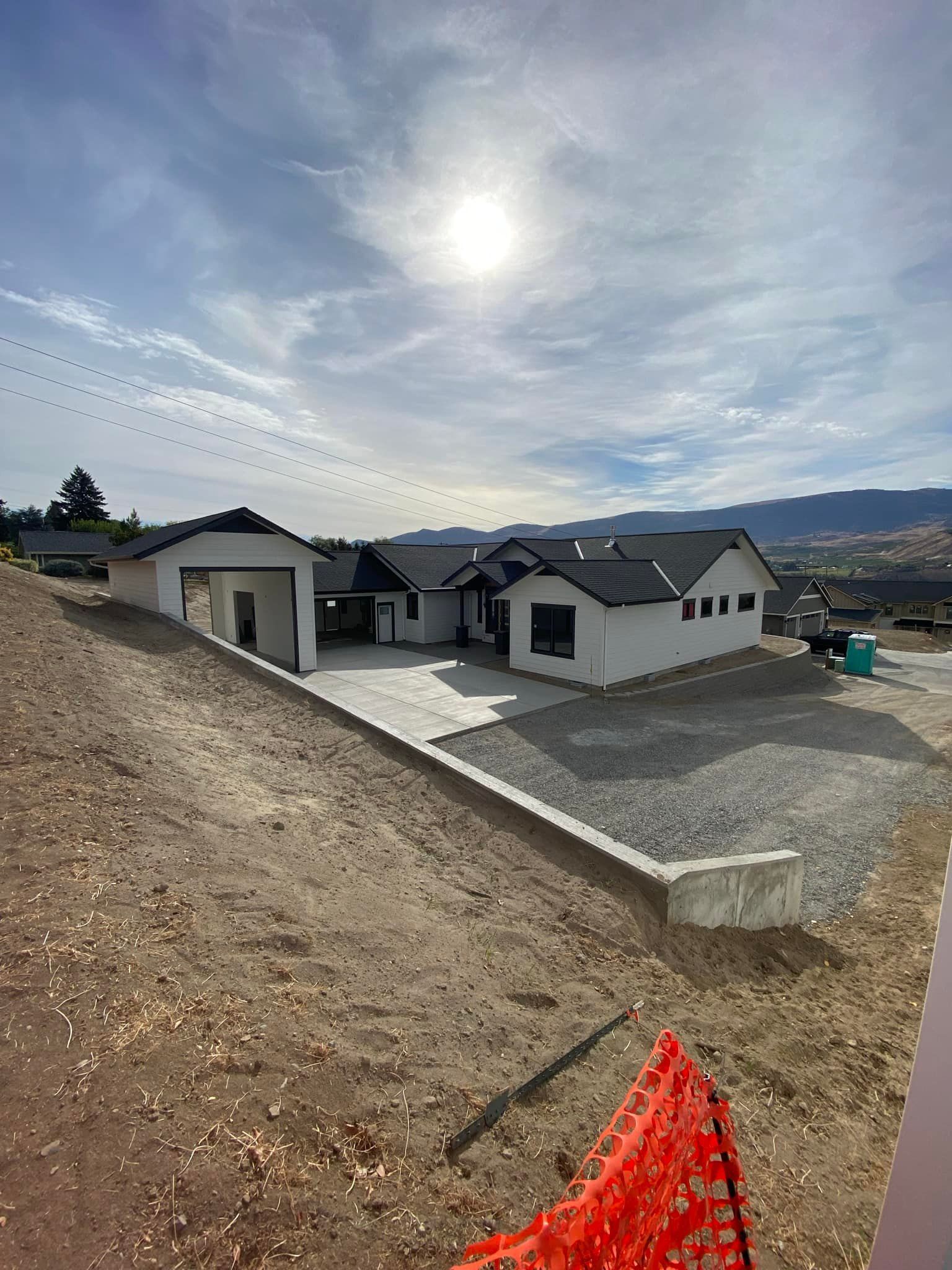 A large white house is sitting on top of a dirt hill.