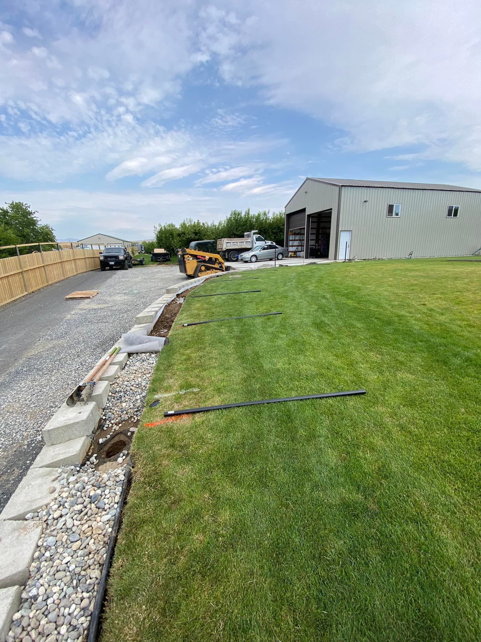 A large building is being built next to a lush green field.