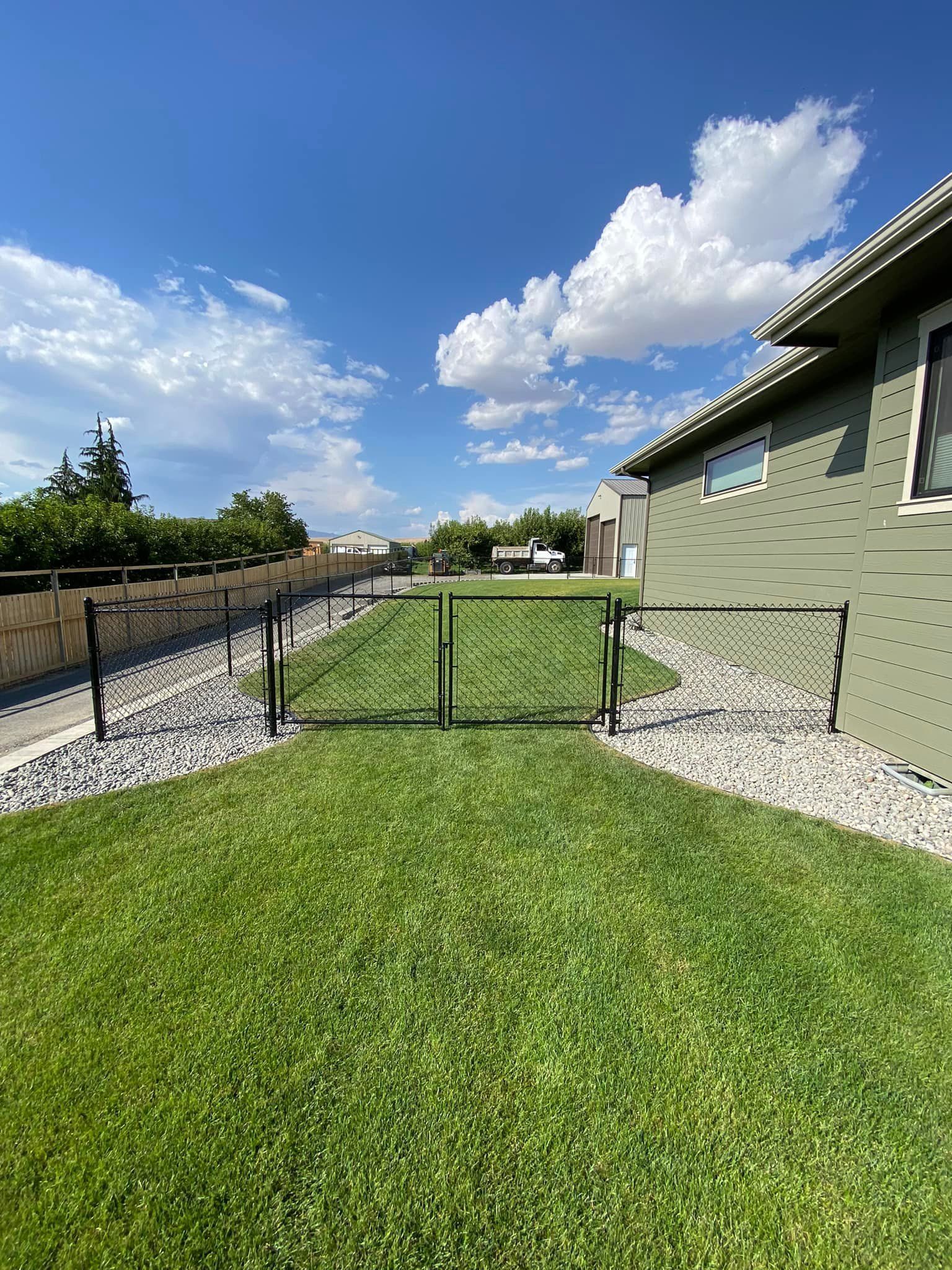 A lush green yard with a fence and a house in the background.