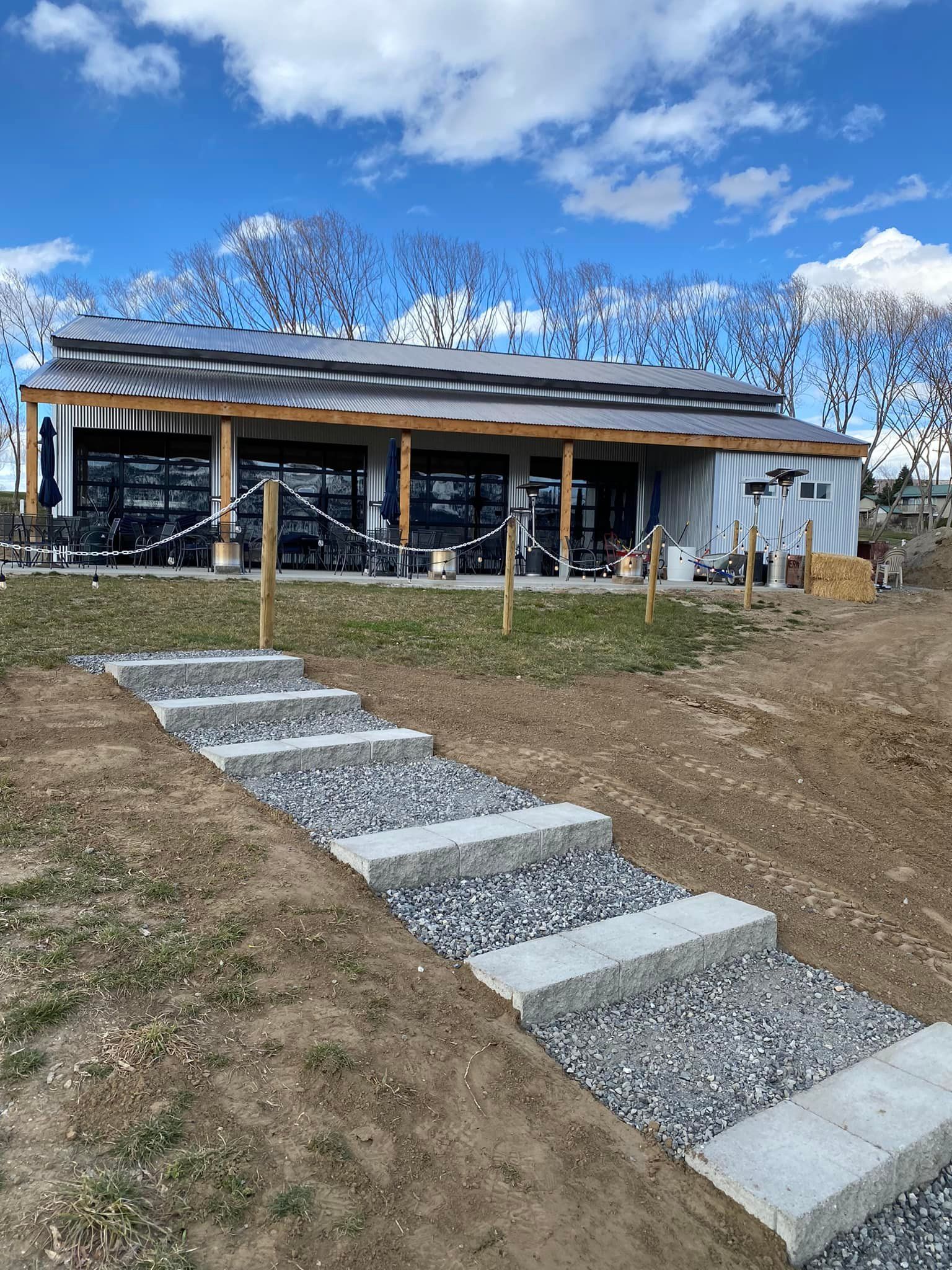 A house with stairs leading up to it is sitting in the middle of a field.
