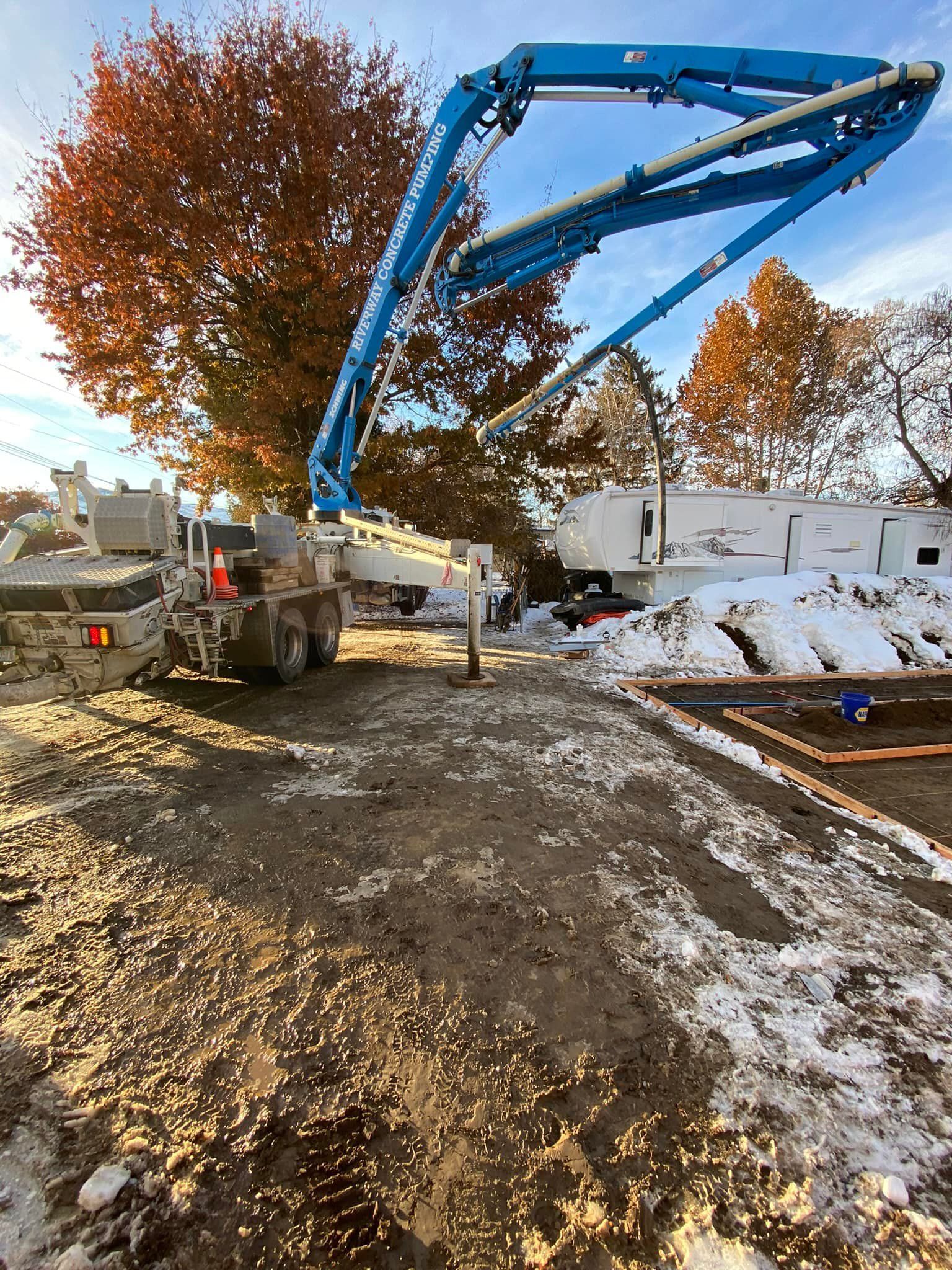 A concrete pump is being used to pour concrete on a dirt road.
