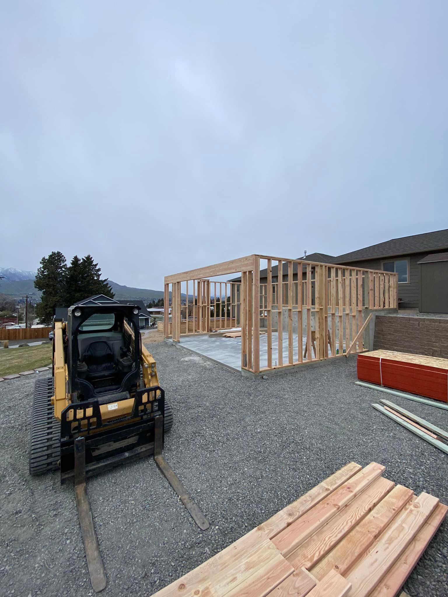 A bulldozer is driving down a gravel road next to a pile of wood.