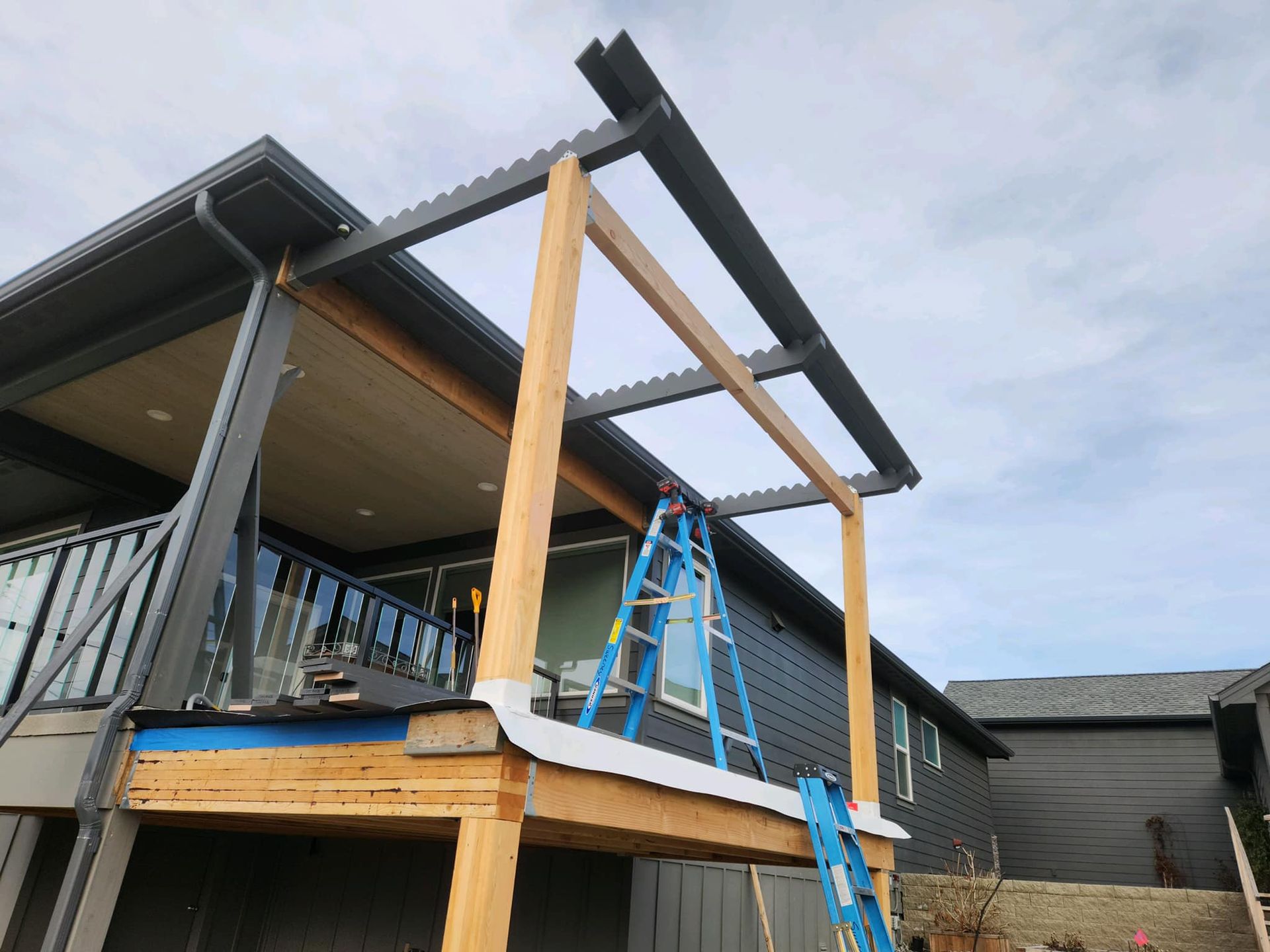 A ladder is sitting on top of a wooden deck in front of a house.