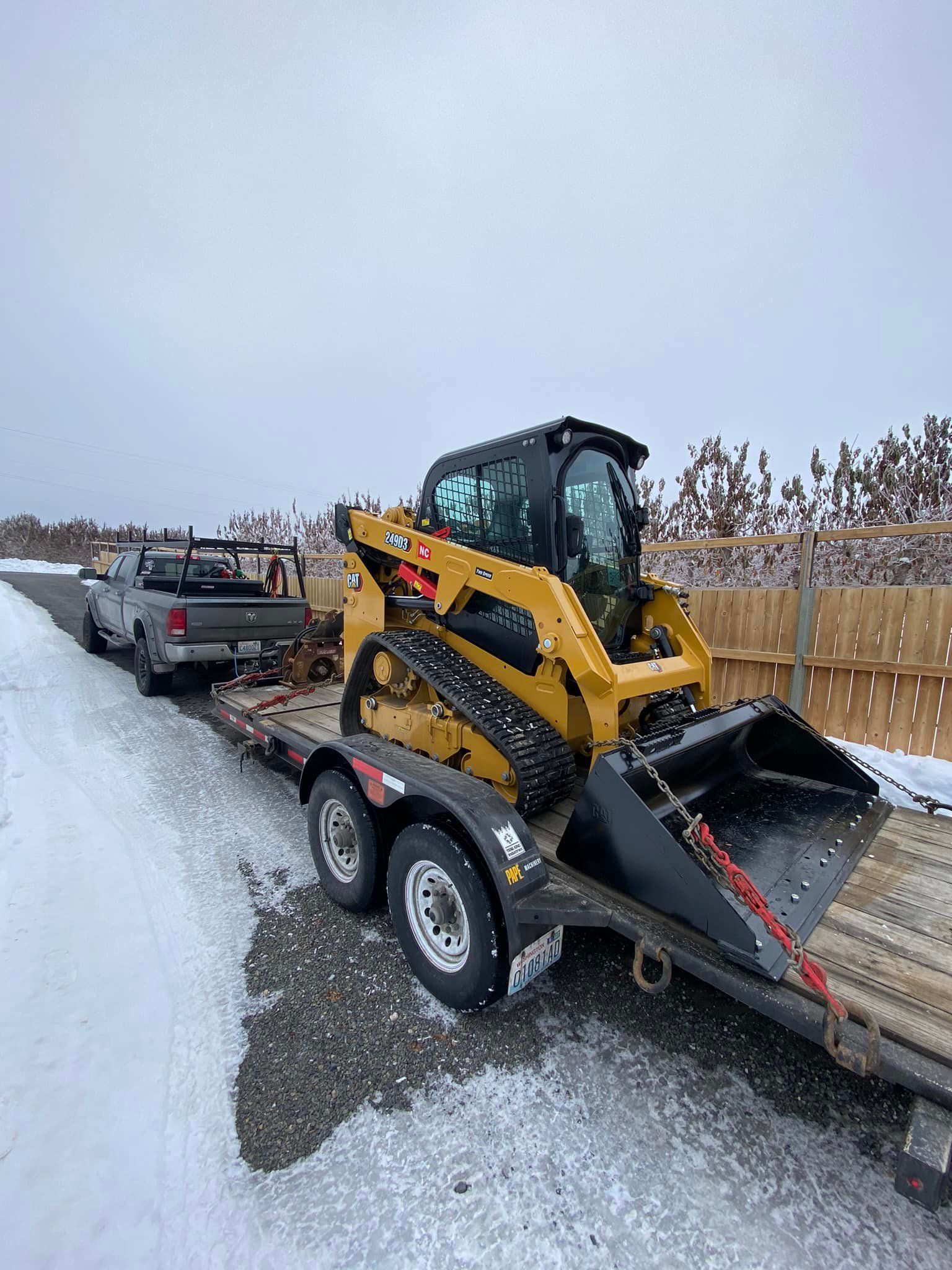 A bulldozer is being towed by a truck on a trailer.