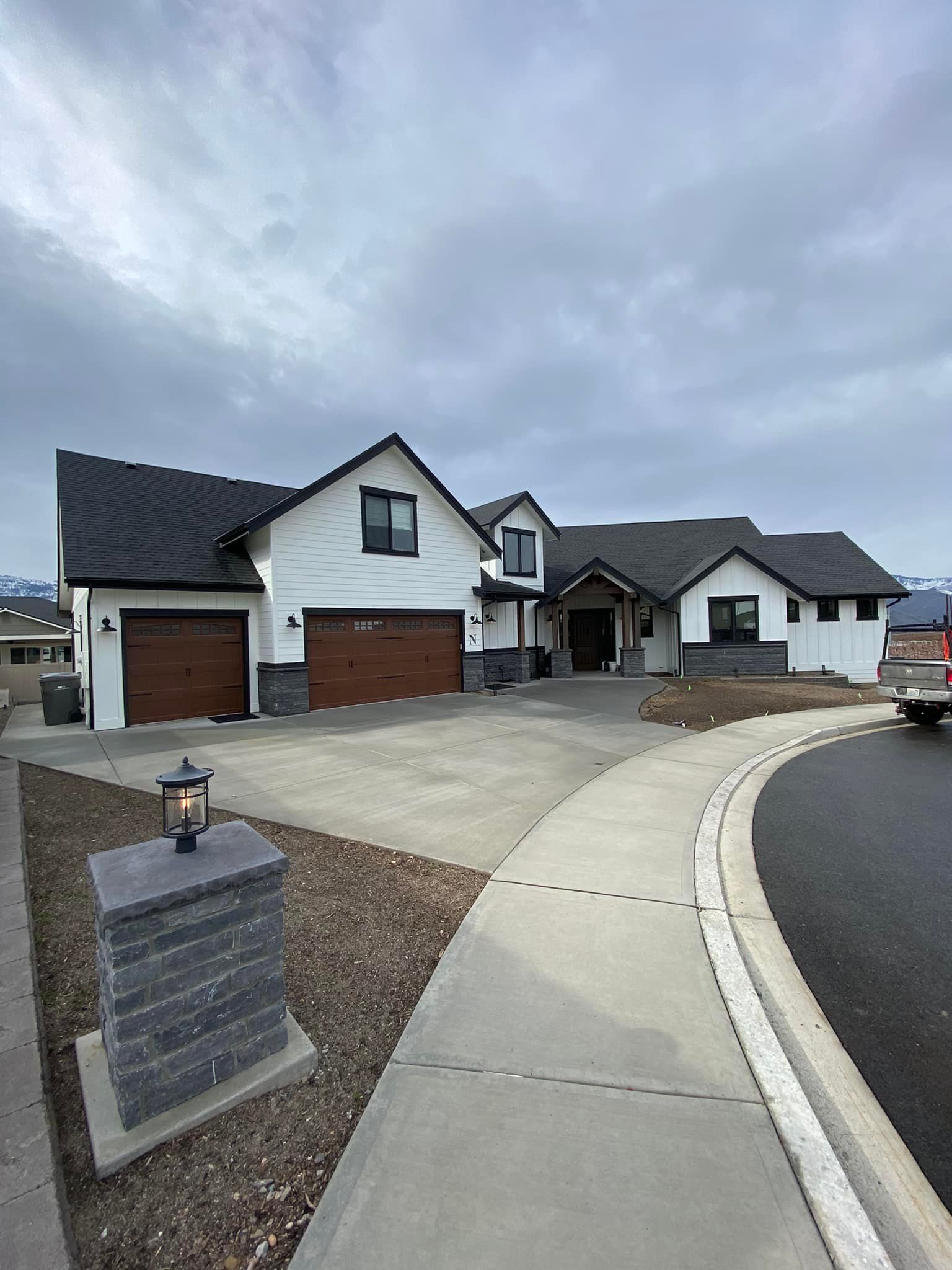 A large white house with a black roof is sitting on top of a lush green hillside.