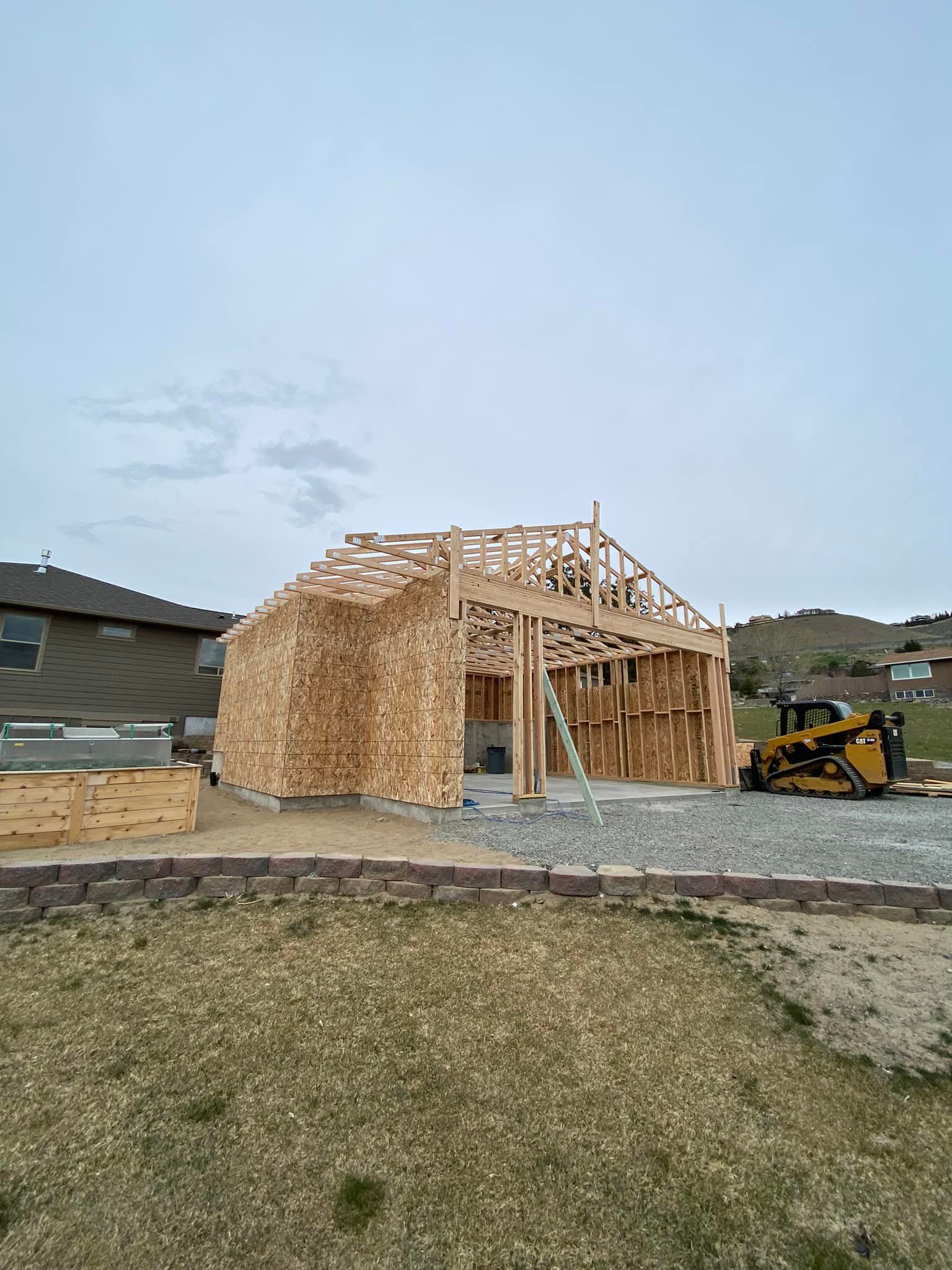 A house is being built with a bulldozer in the background.