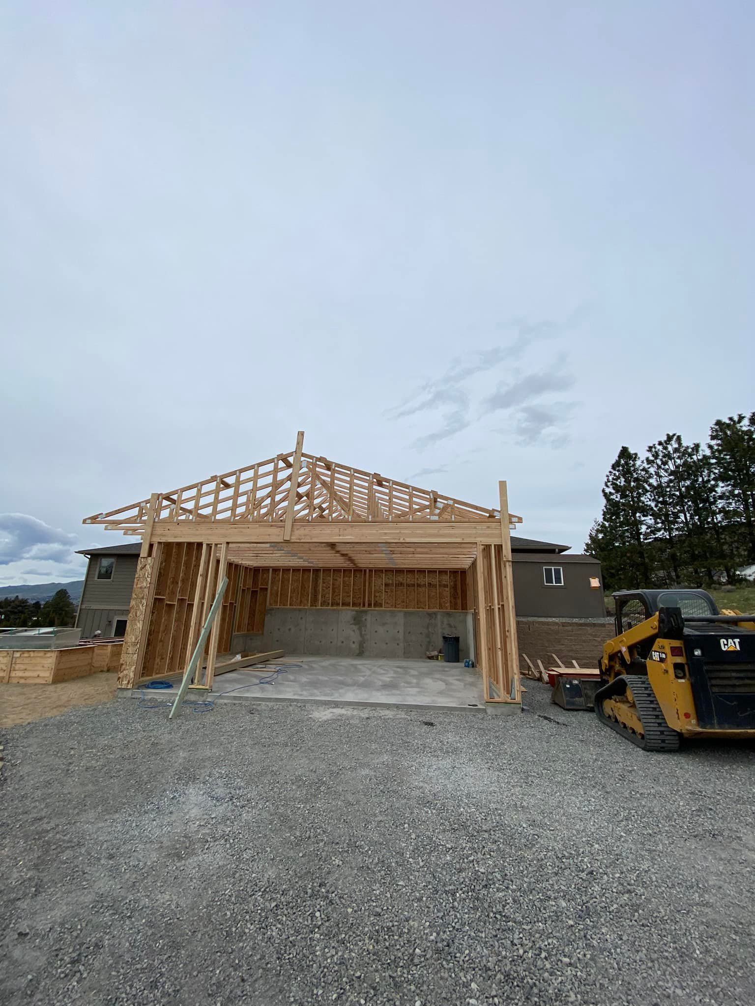 A house is being built and a bulldozer is parked in front of it.