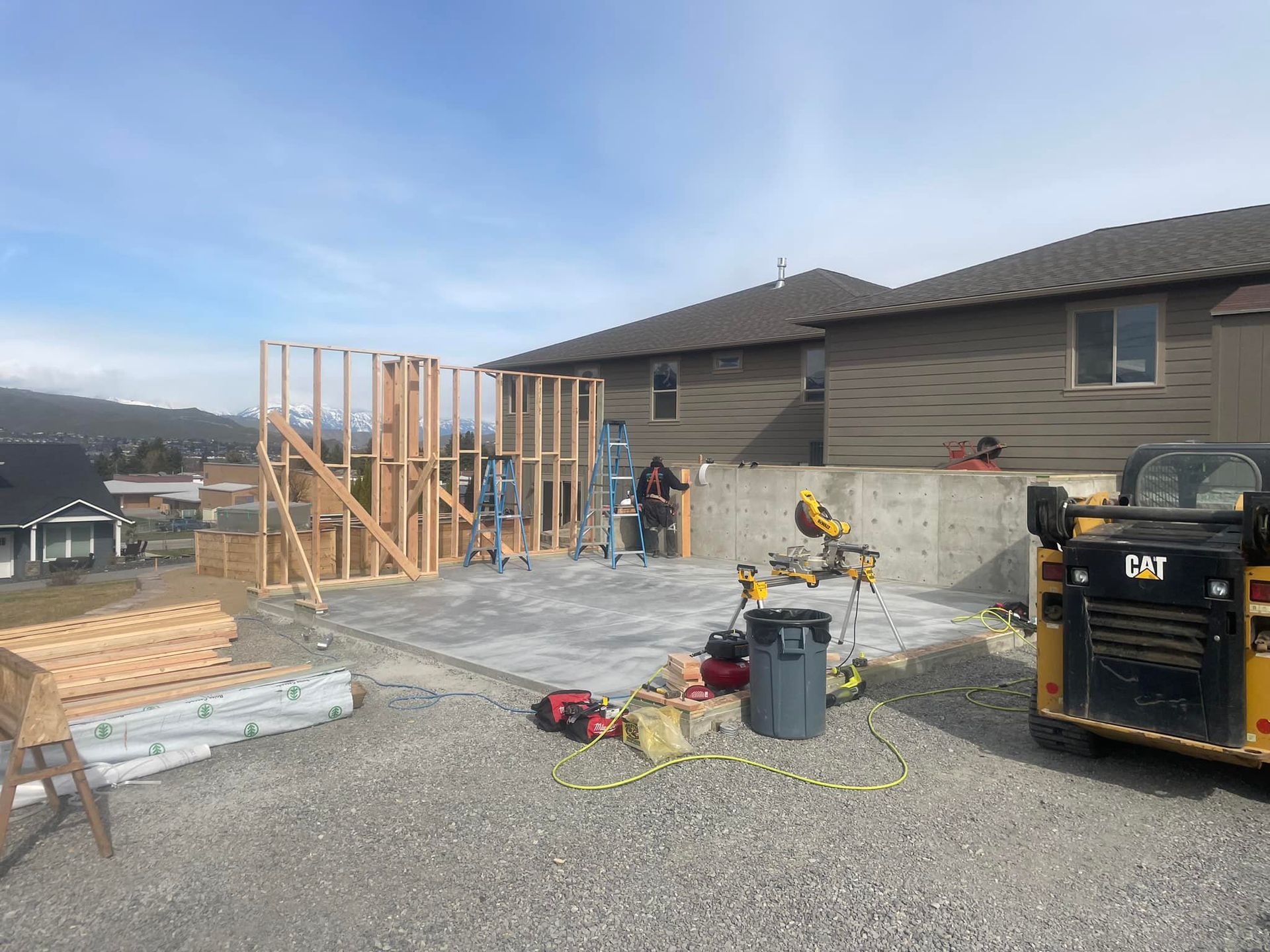 A house is being built and a bulldozer is parked in front of it.