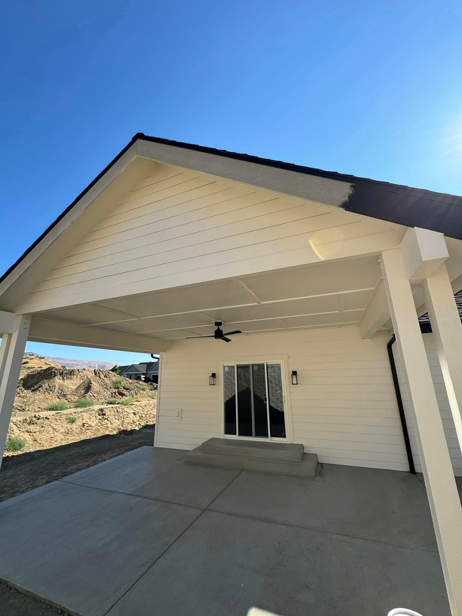 A white house with a covered porch and a ceiling fan.