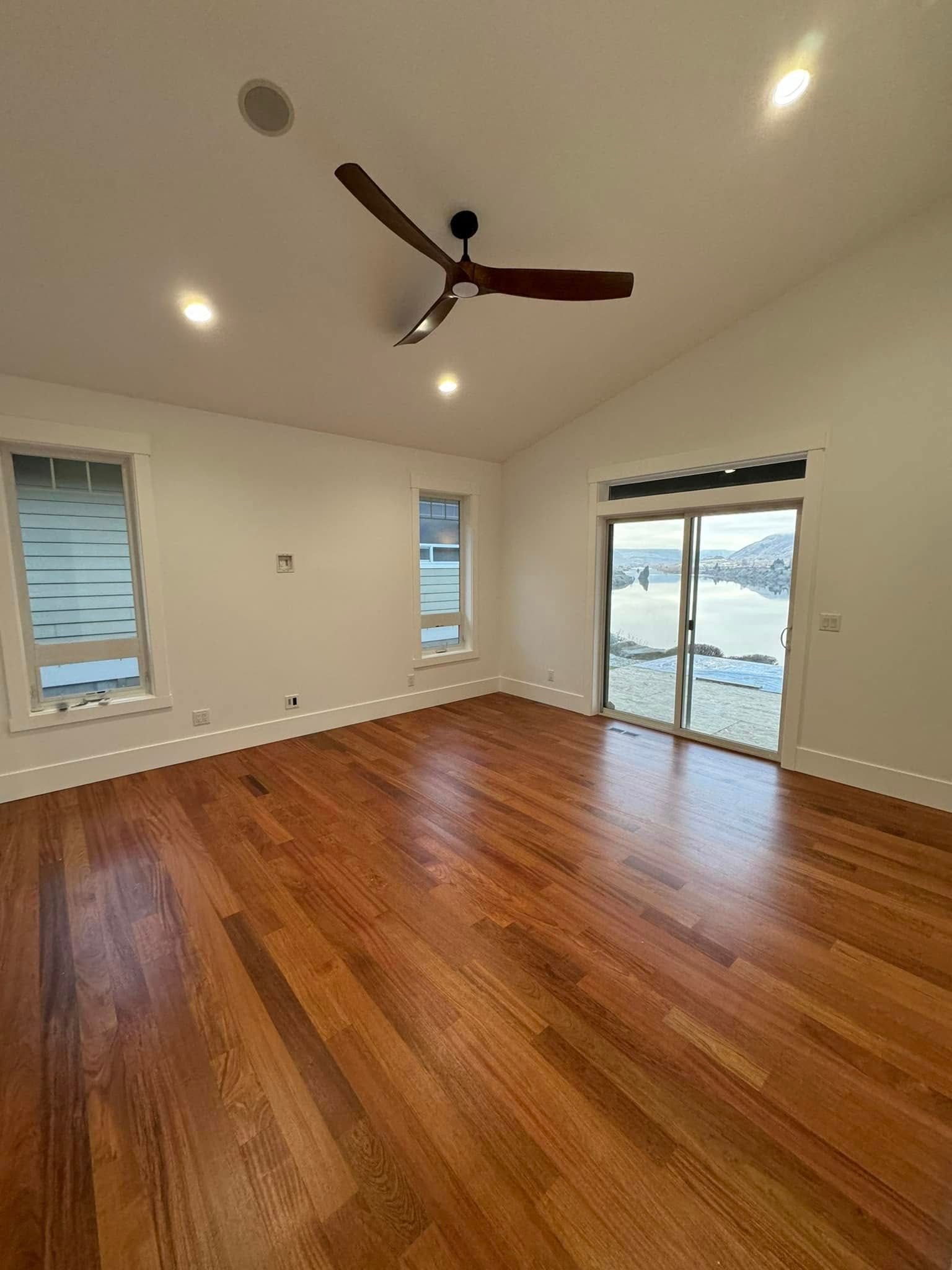 An empty room with hardwood floors and a ceiling fan.
