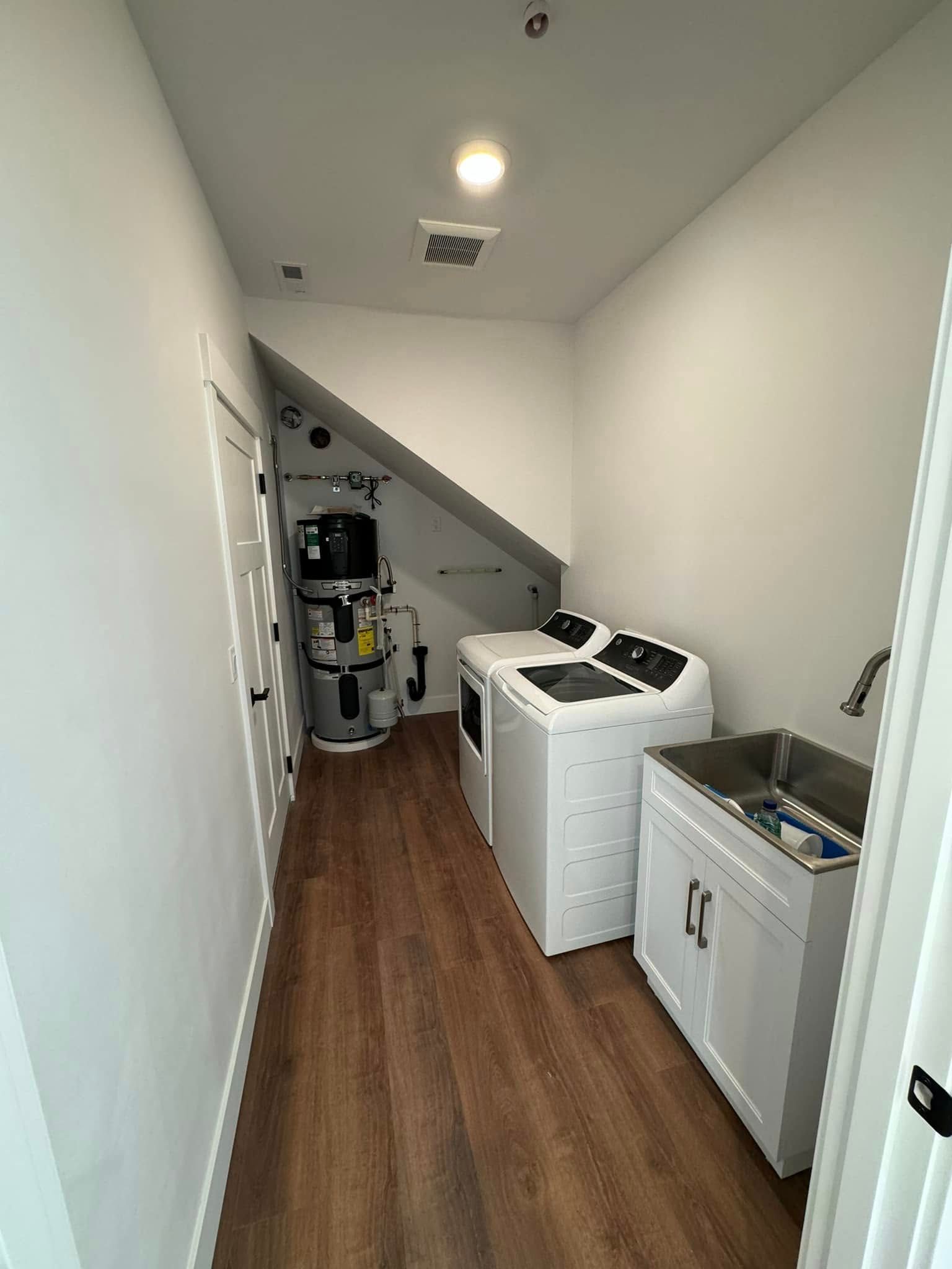 A laundry room with a washer and dryer and a sink.