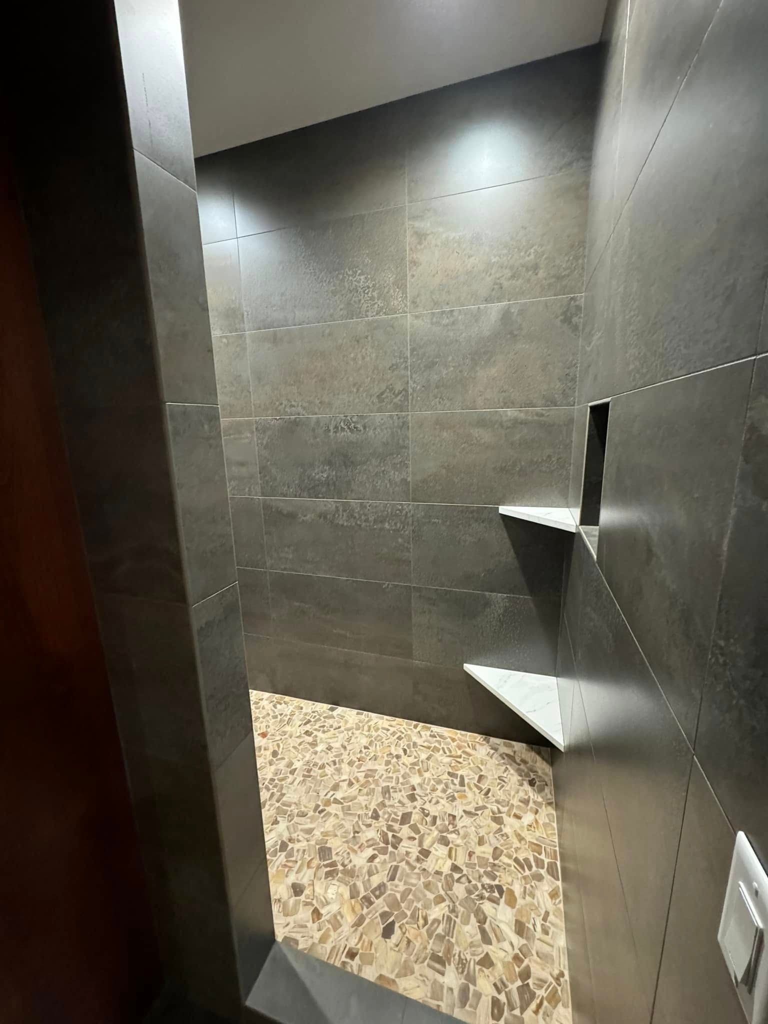 A bathroom with black tiles and a walk in shower.