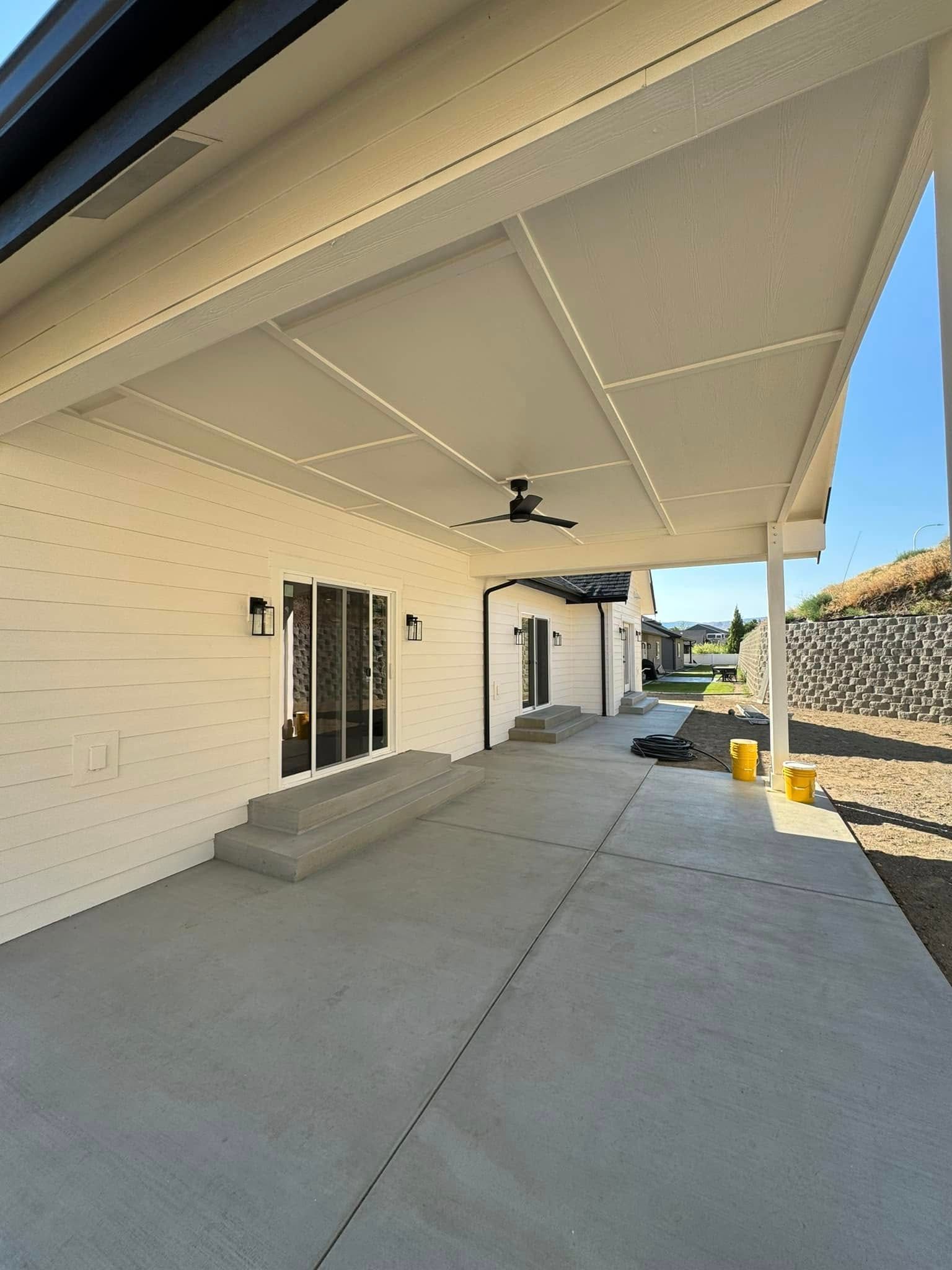 A white house with a covered patio and a ceiling fan.