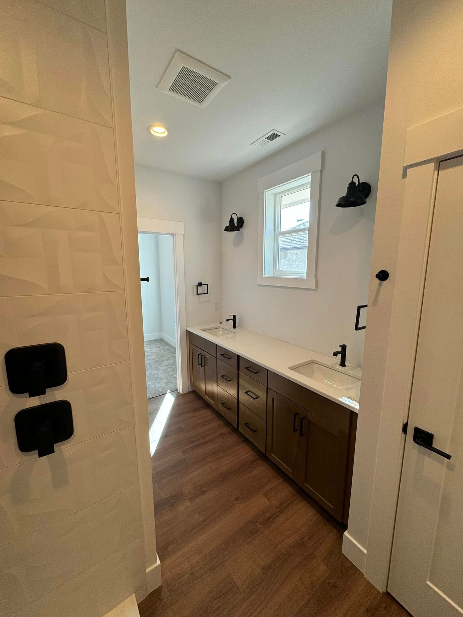 A bathroom with a sink , cabinets , and a window.