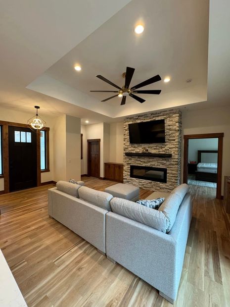 A living room with a couch , fireplace , television and ceiling fan.
