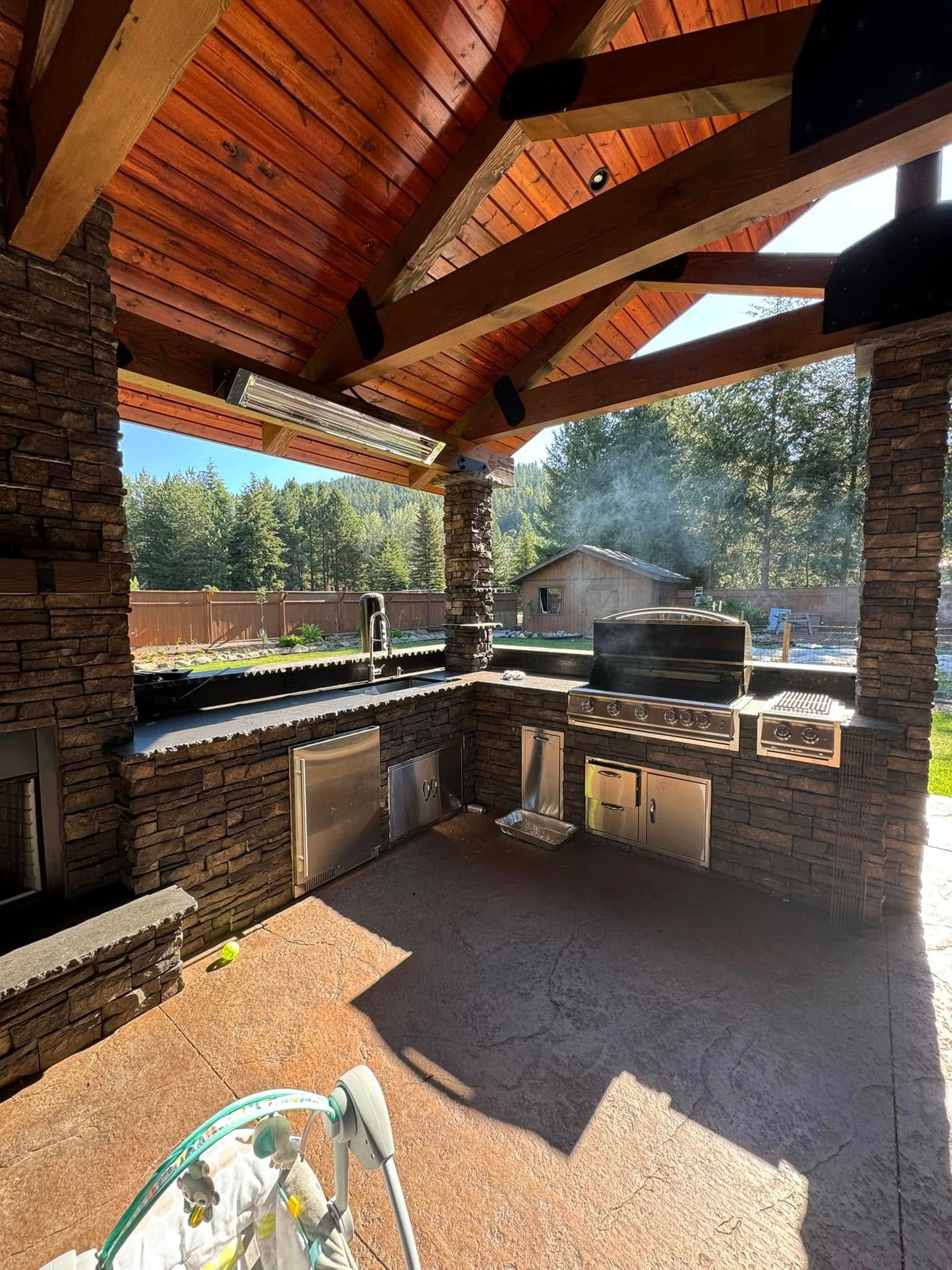 A large outdoor kitchen with a wooden ceiling and a grill.