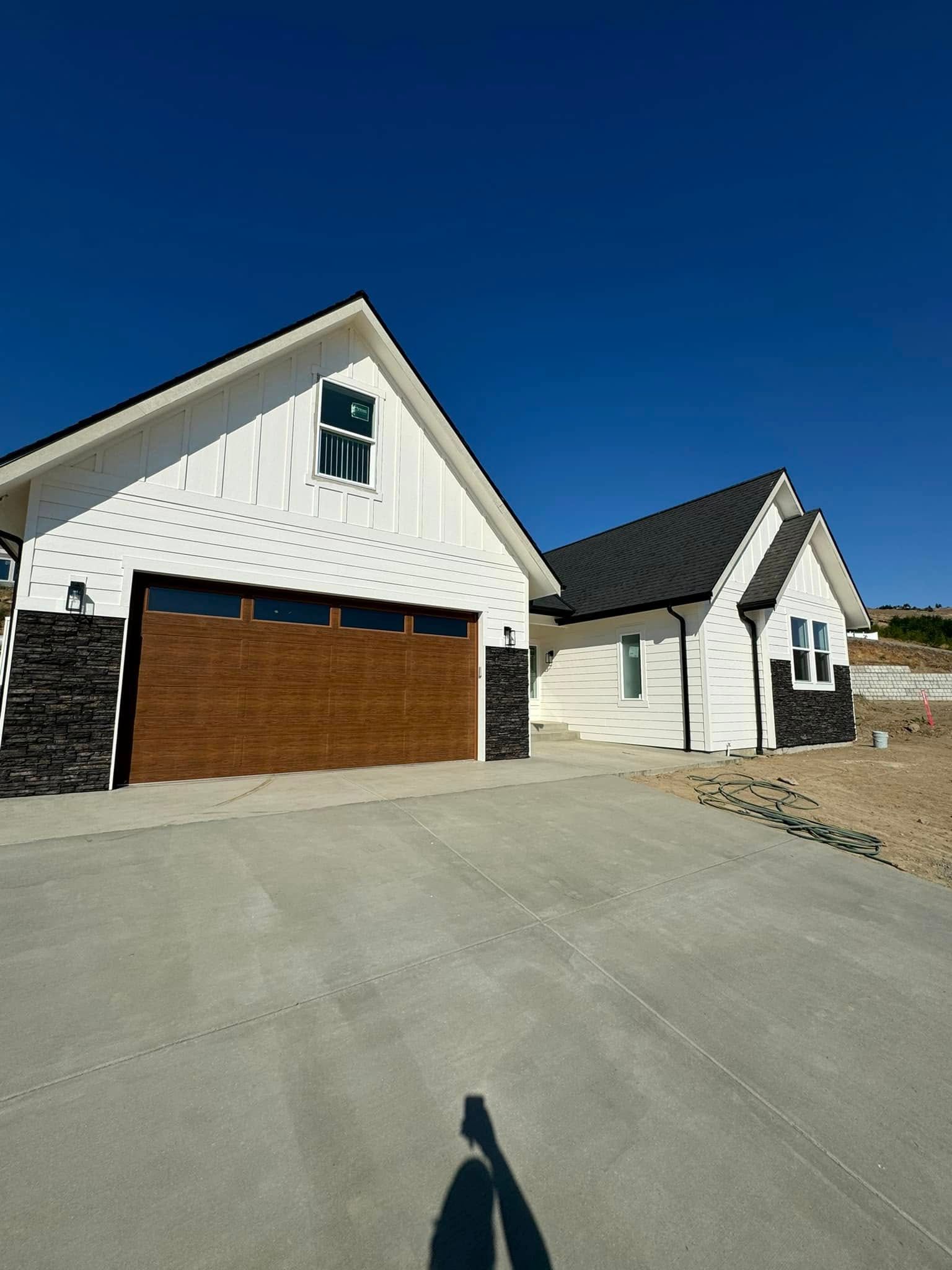 A white house with a brown garage door and a blue sky in the background.